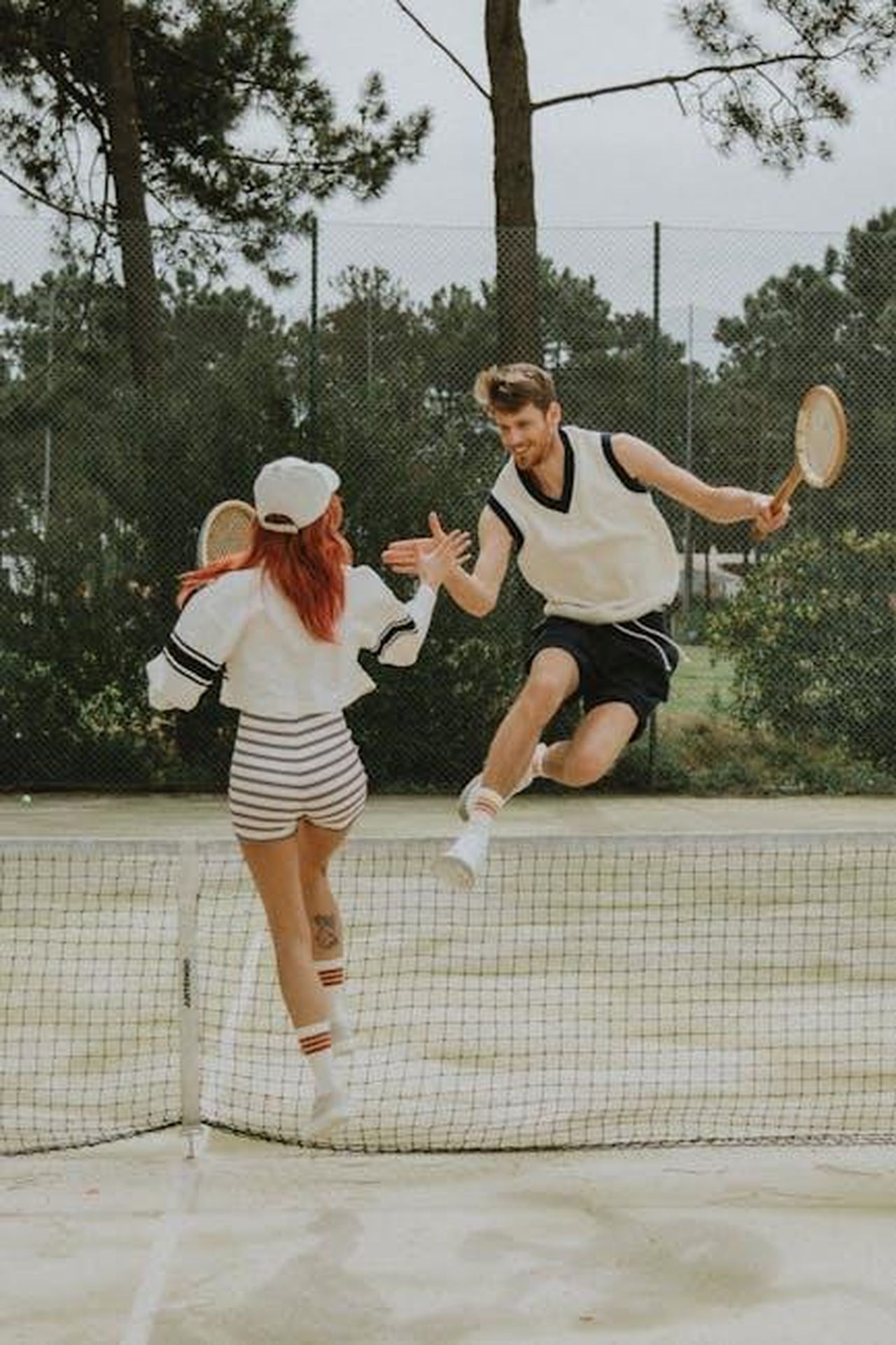 La_situazione_finanziaria_di_Jackman_e_Foster_tizp44HiWo - Confidenze24 Source: Erwans Socks - pexels - Energetic moment of a couple high-fiving over a tennis net in an outdoor setting.