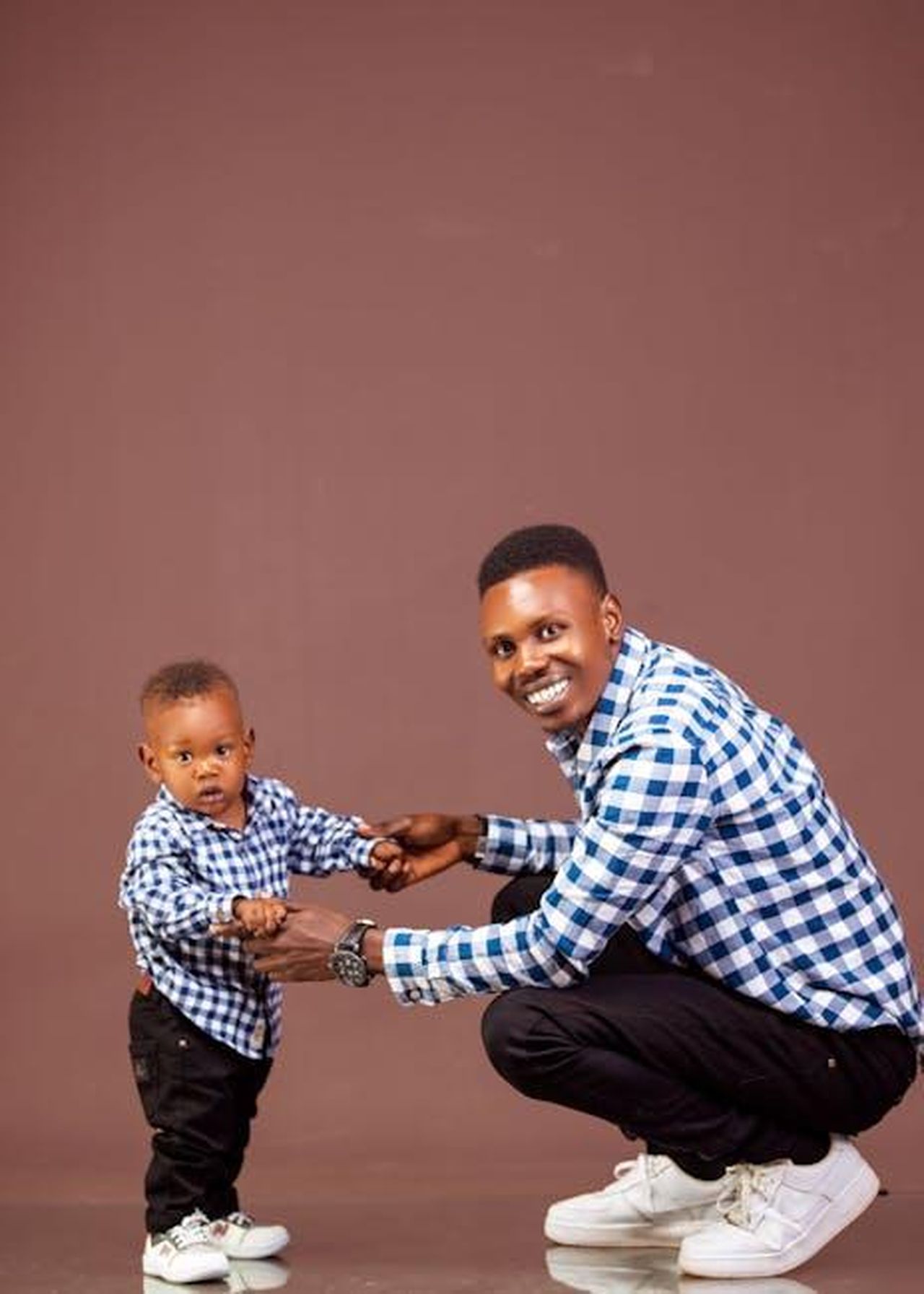 La_somiglianza_tra_Keke_e_Leo_cA9kSRDAkq - Confidenze24 Source: Mika Photogenius - pexels - Father and son smiling while wearing matching plaid shirts and sneakers in a studio setting.