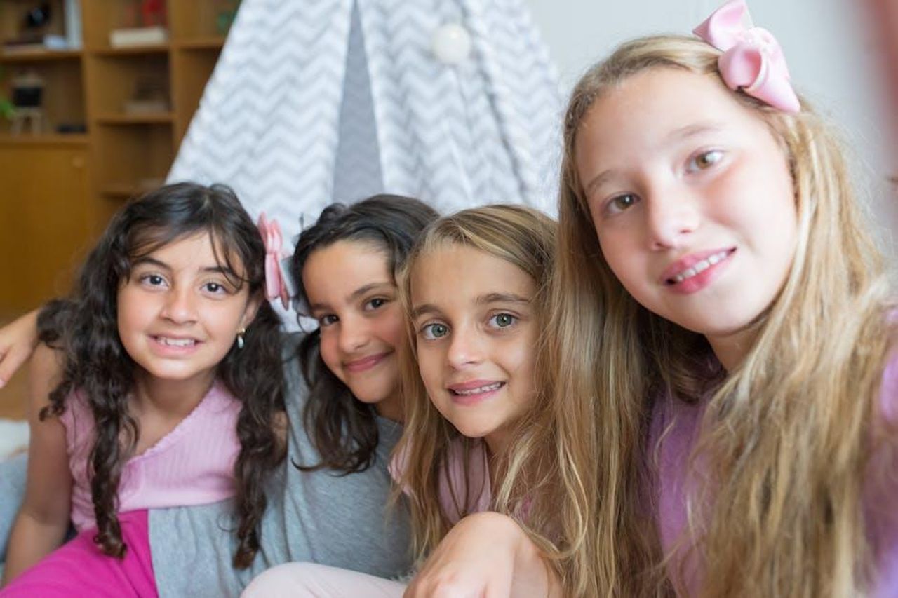 La_somiglianza_tra_Sterling_e_Bronze_Jn0G9eRhb9 - Confidenze24 Source: Kampus Production - pexels - Four smiling young girls sitting close, taking a selfie indoors.