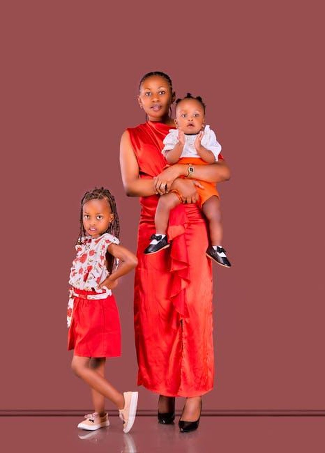 La_somiglianza_tra_le_gemelle_e_la_madre_arfZC3nJX6 - Confidenze24 Source: Mika Photogenius - pexels - A mother and two daughters in matching red outfits pose gracefully.