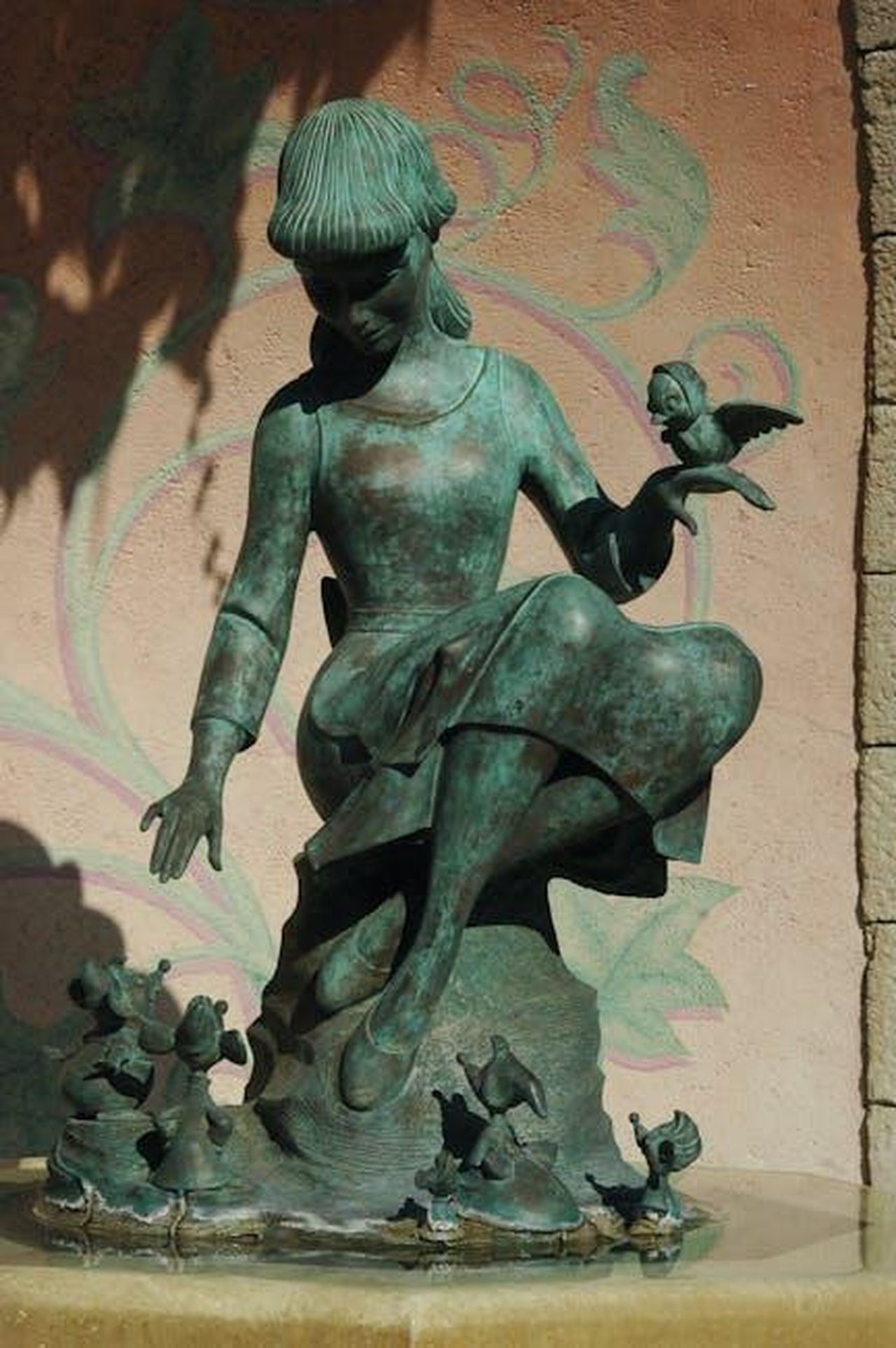 La_storia_da_favola_di_Meghan_Markle_1XdbZYbhXd - Confidenze24 Source: CARLOSCRUZ ARTEGRAFIA - pexels - Captivating bronze statue of a girl with birds, surrounded by playful figures in a detailed fountain setting.