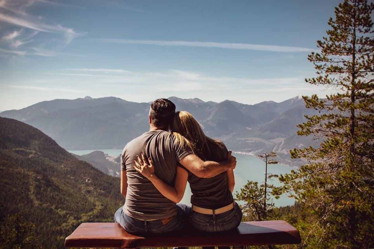 La_storia_damore_di_Daddario_e_Andrew_Form_vzJHJ6cbeW - Confidenze24 Source: Andre Furtado - pexels - Couple sitting on bench embracing scenic mountain view, embodying romantic nature escape.