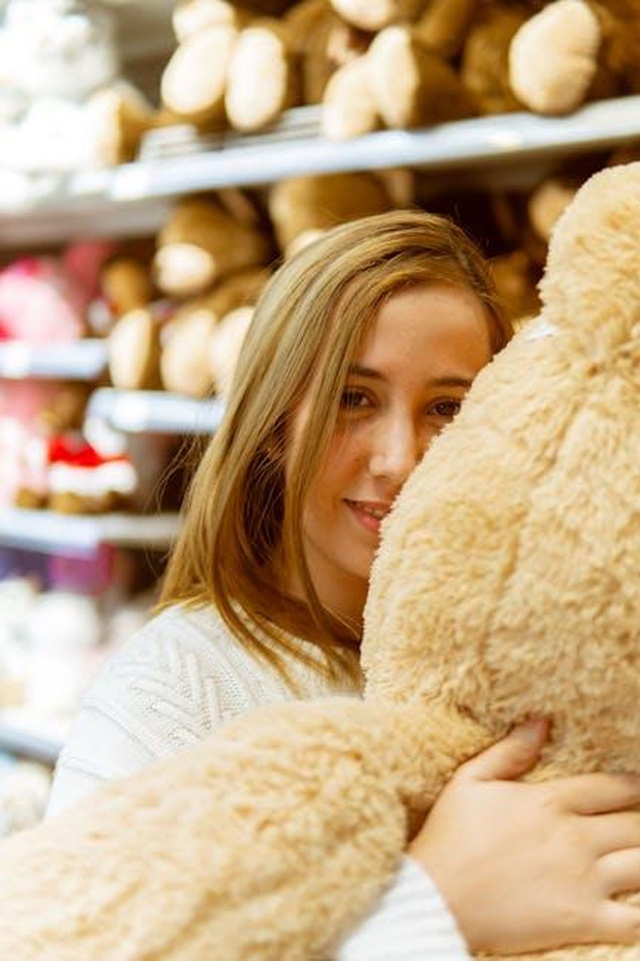 La_storia_damore_di_Devin_e_Virginia_vKxx9O16Ij - Confidenze24 Source: Hassan OUAJBIR - pexels - A blonde woman smiling while hugging a large teddy bear in a store.