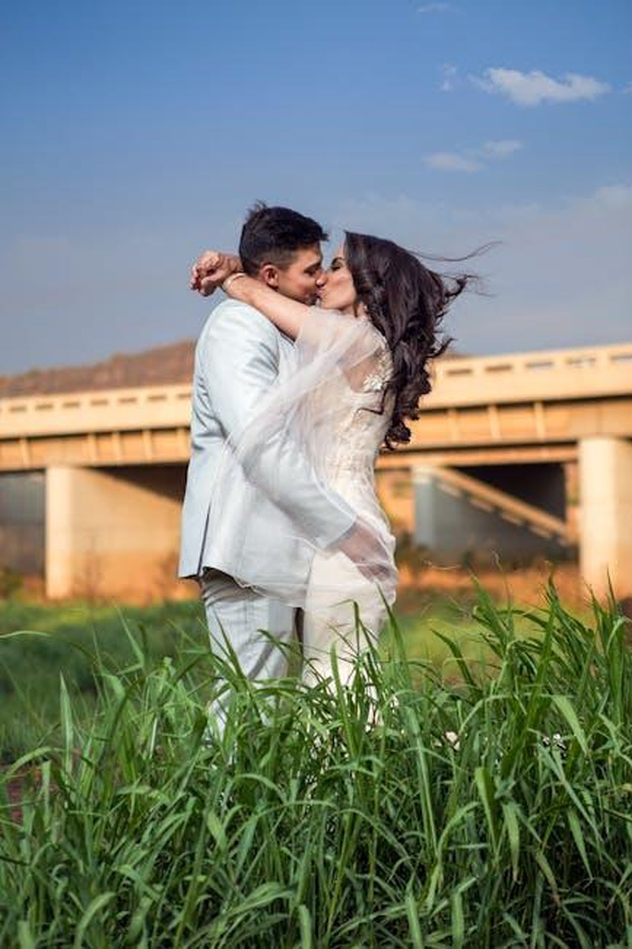 La_storia_damore_tra_Affleck_e_Garner_AkCwSug3Ro - Confidenze24 Source: Lood Goosen - pexels - A young couple embraces and kisses in a field near a bridge, showcasing love and romance.