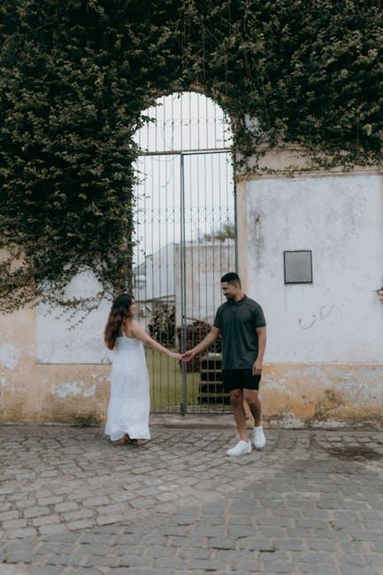 La_storia_di_Hoda_e_Joel_SF0PqA3gGU - Confidenze24 Source: Alexander Mass - pexels - Couple holding hands in front of a rustic ivy-covered wall, conveying romance.