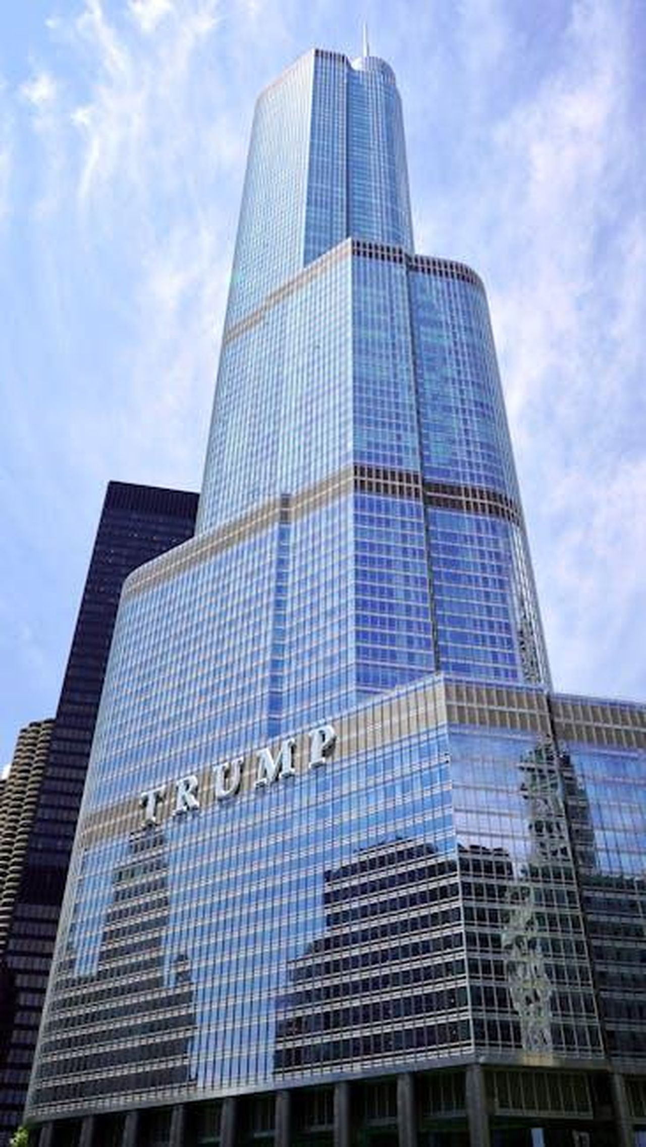 La_storia_di_Vanessa_e_Donald_Trump_Jr_1xRceGMztz - Confidenze24 Source: Priya Karkare - pexels - Low angle view of a modern skyscraper with reflective glass facade against a clear sky.