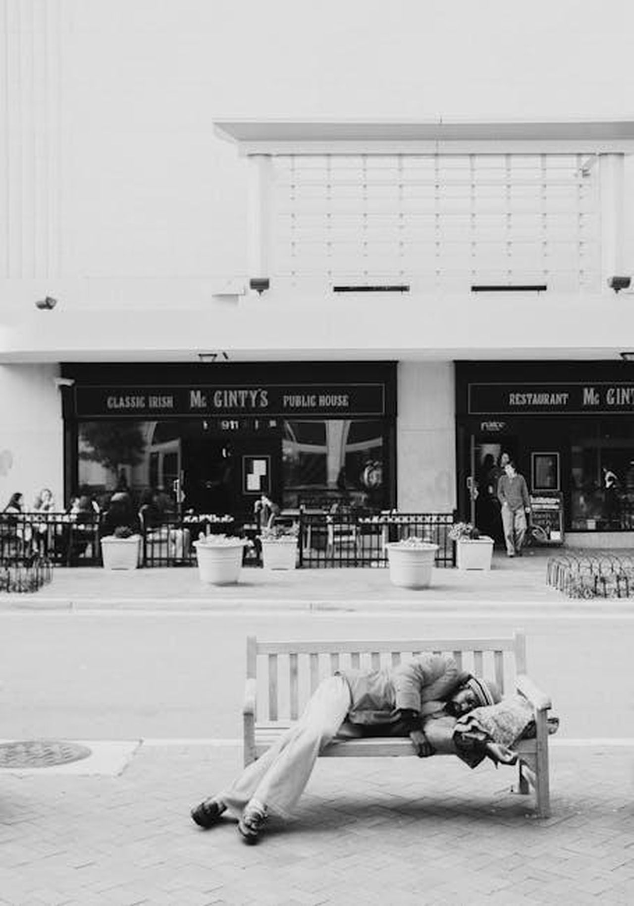 La_storia_travagliata_di_Blaze_KlHCx4CKtL - Confidenze24 Source: Harun Tan - pexels - A man rests on a street bench in Arlington, VA, with a restaurant in the background.