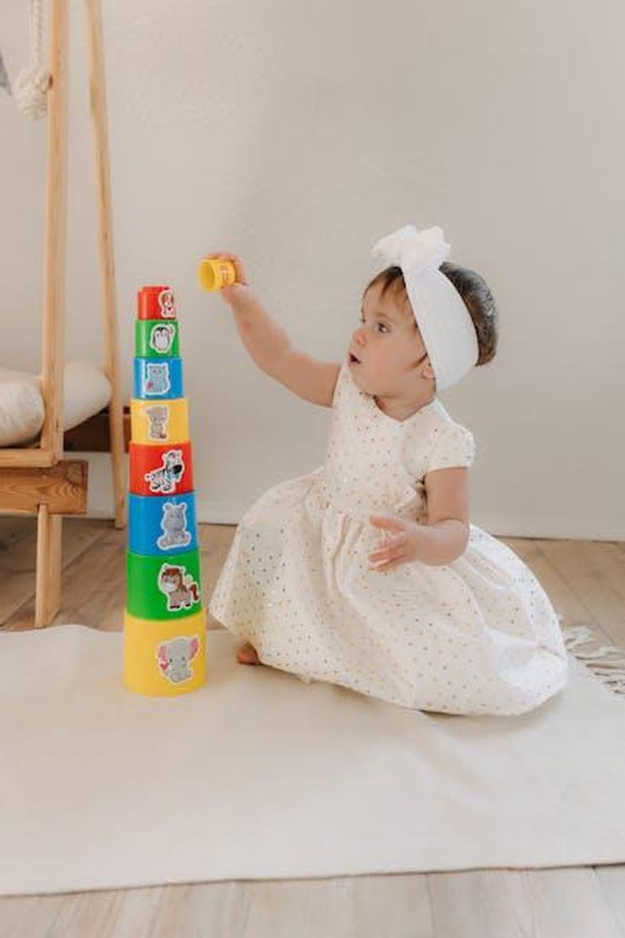 La_strategia_di_Paris_per_un_ambiente_sicuro_VzX2zAjX80 - Confidenze24 Source: Polesie Toys - pexels - Cute baby girl in a white dress playing with colorful stacking toys indoors.