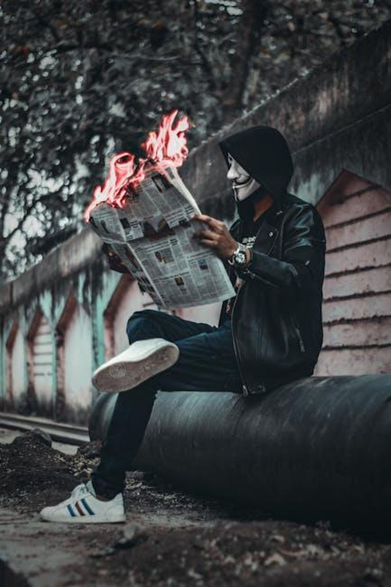 La_verit_viene_a_galla_xXQ5xaglgQ - Confidenze24 Source: Ashutosh Sonwani - pexels - A person wearing a mask reads a flaming newspaper on an urban street, creating a surreal and mysterious scene.