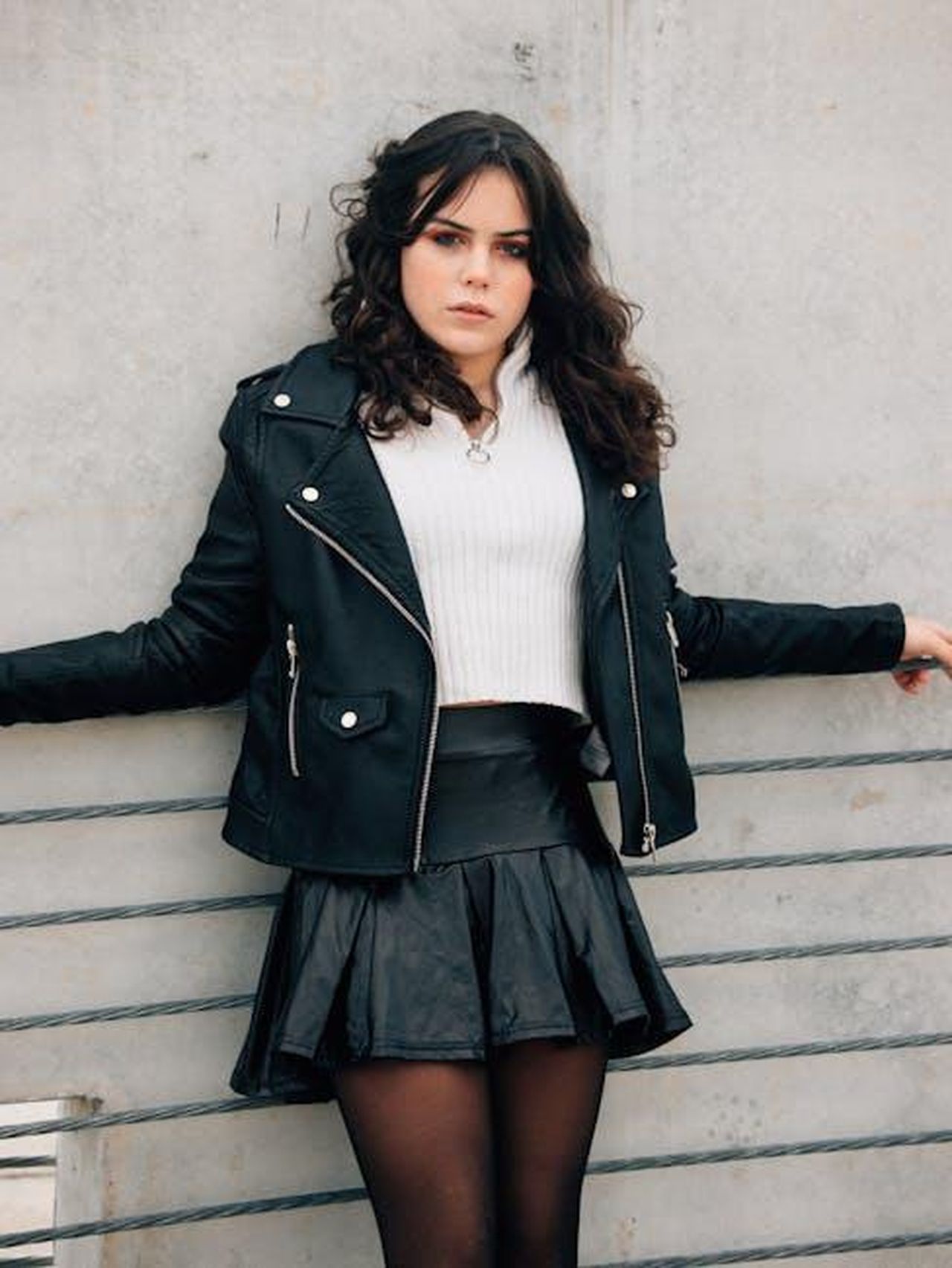 La_vita_di_Jimmy_Stewart_e_la_sua_carriera_OOZWYBTfea - Confidenze24 Source: Sherman Trotz - pexels - Young woman leaning on fence in stylish black leather jacket, exuding confidence.
