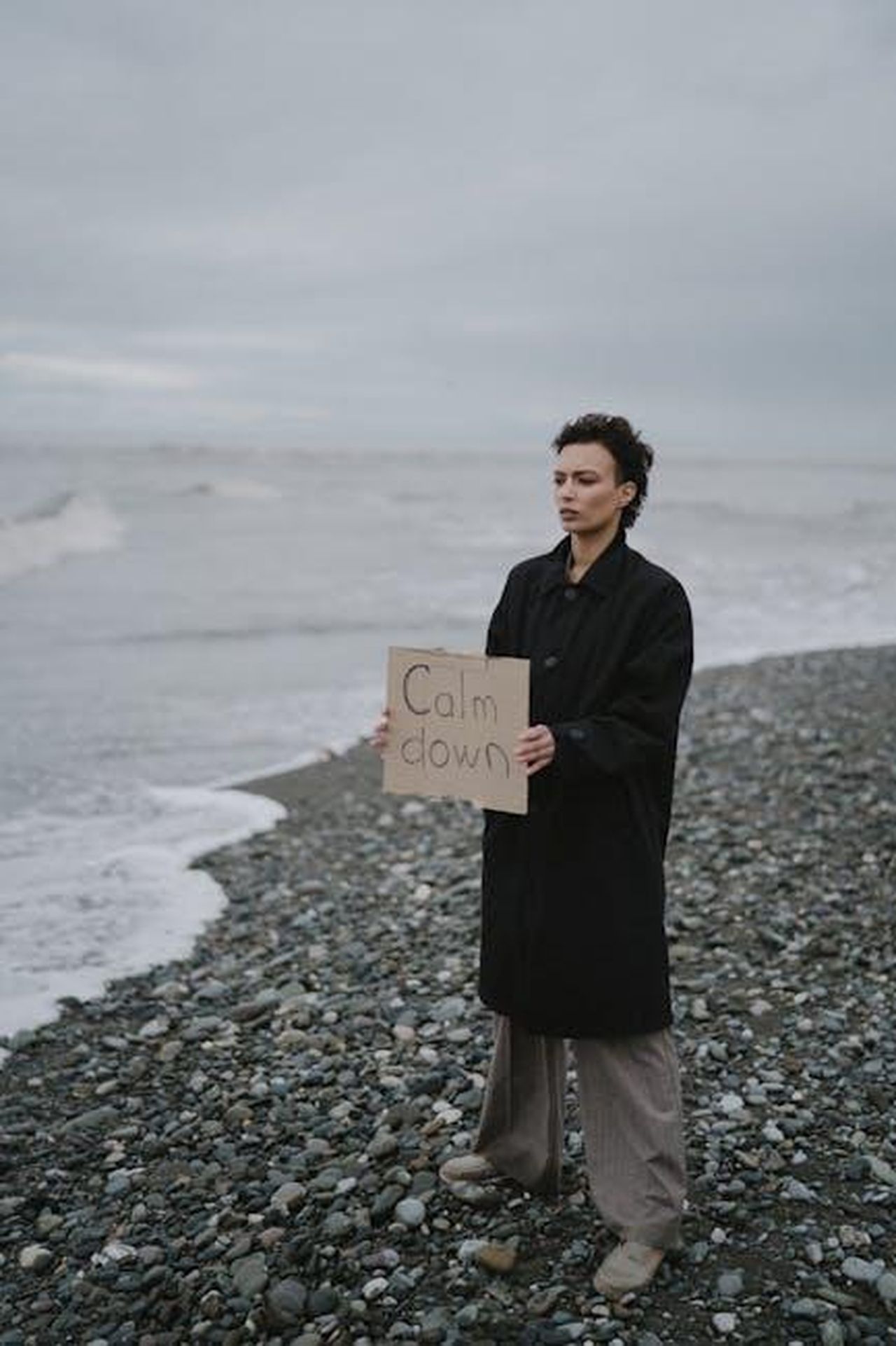 La_vita_di_Kendra_dopo_il_divorzio_bKPdugkgxZ - Confidenze24 Source: Anastasia Shuraeva - pexels - Person stands on a beach holding a 'Calm Down' sign, symbolizing serenity and mindfulness.