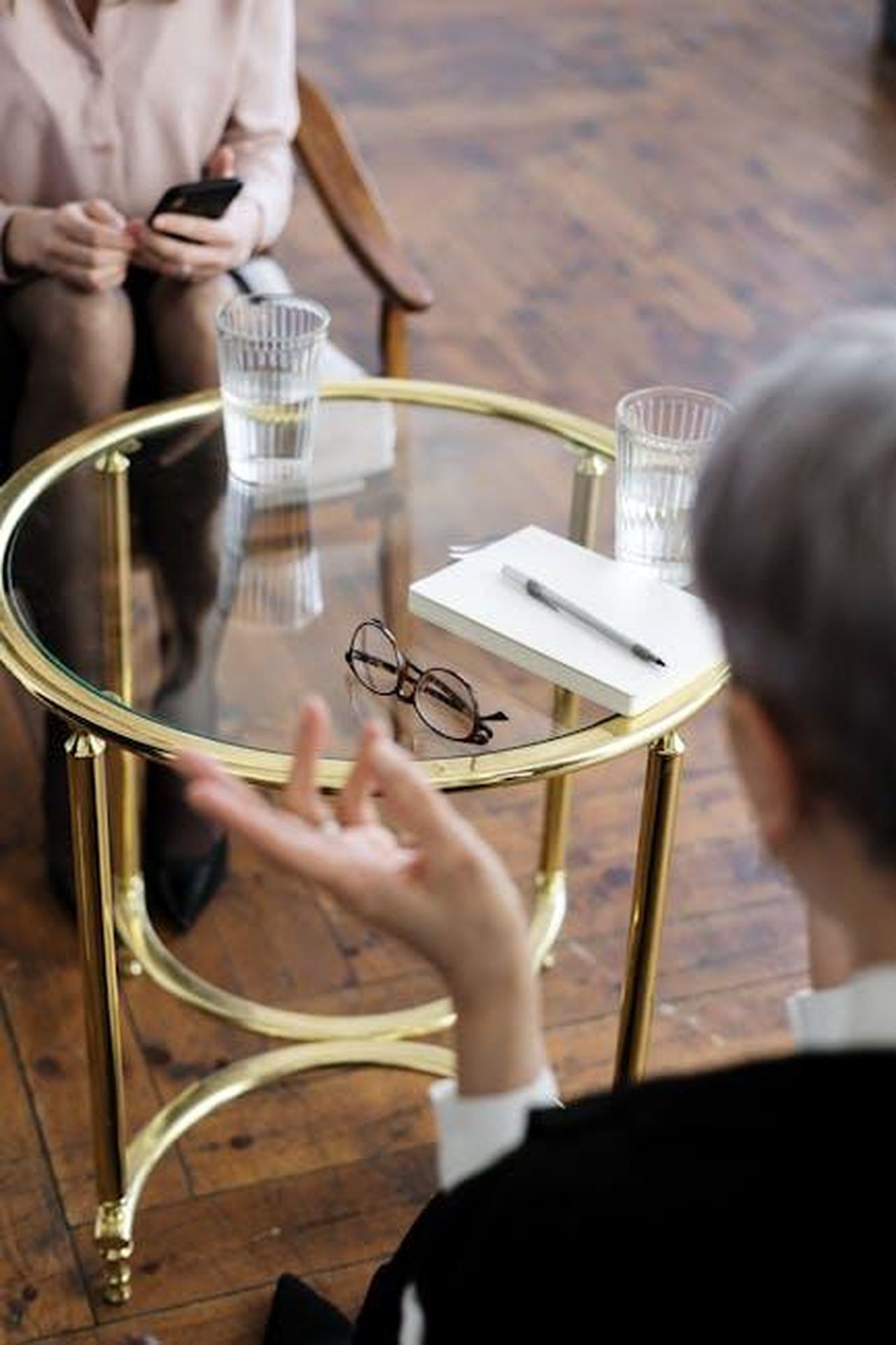 La_vita_dopo_il_divorzio_da_Baumgartner_0A3KpkXYr0 - Confidenze24 Source: cottonbro studio - pexels - Two adults engaged in a therapy session, seated at a glass table with notebooks and water glasses.