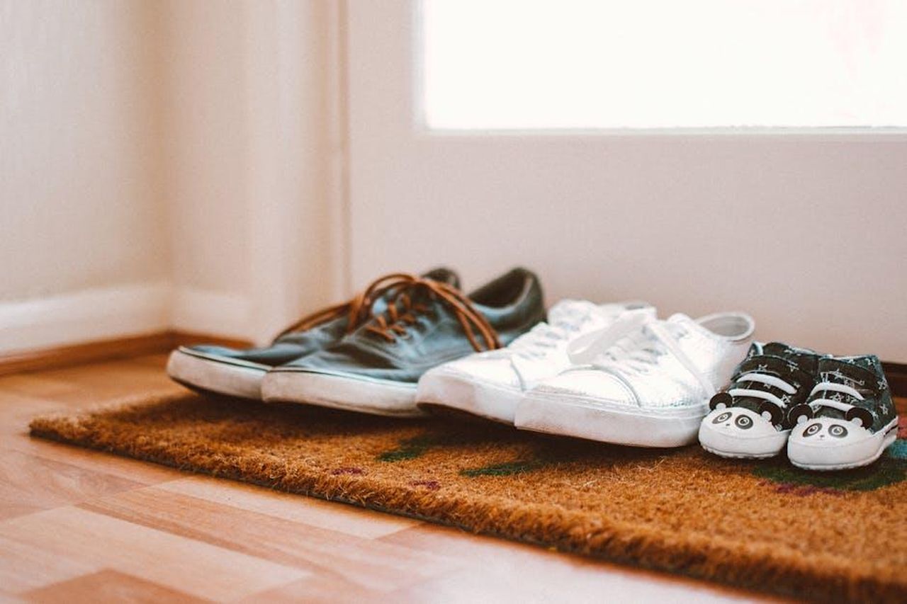 La_vita_familiare_di_Tom_Brady_W6oq0a83AX - Confidenze24 Source: Lisa from Pexels - pexels - Cozy family shoes on a doormat at home entrance, symbolizing warmth and connection.