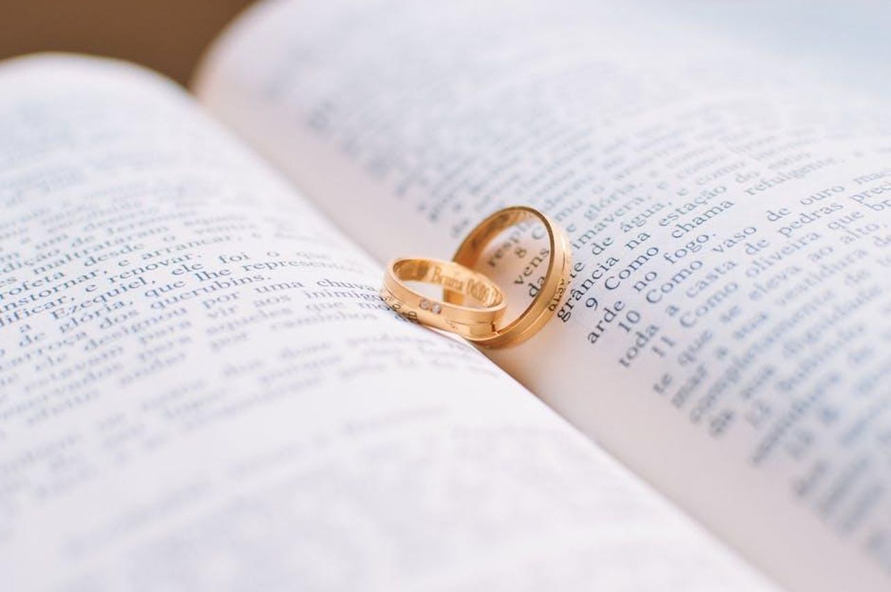La_vita_matrimoniale_di_Dr_Mimi_hlLR46j1PJ - Confidenze24 Source: Caio - pexels - Close-up of wedding rings resting on the pages of an open book, symbolizing love and commitment.
