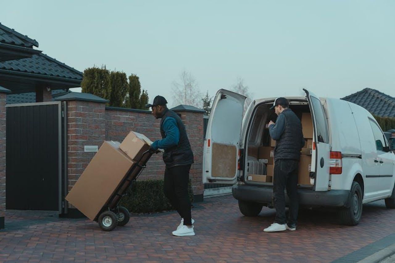 La_vita_privata_di_Dolly_e_Carl_Dean_EL2dJ21DZJ - Confidenze24 Source: Tima Miroshnichenko - pexels - Two delivery men working diligently from a van, showing teamwork and logistics efficiency.