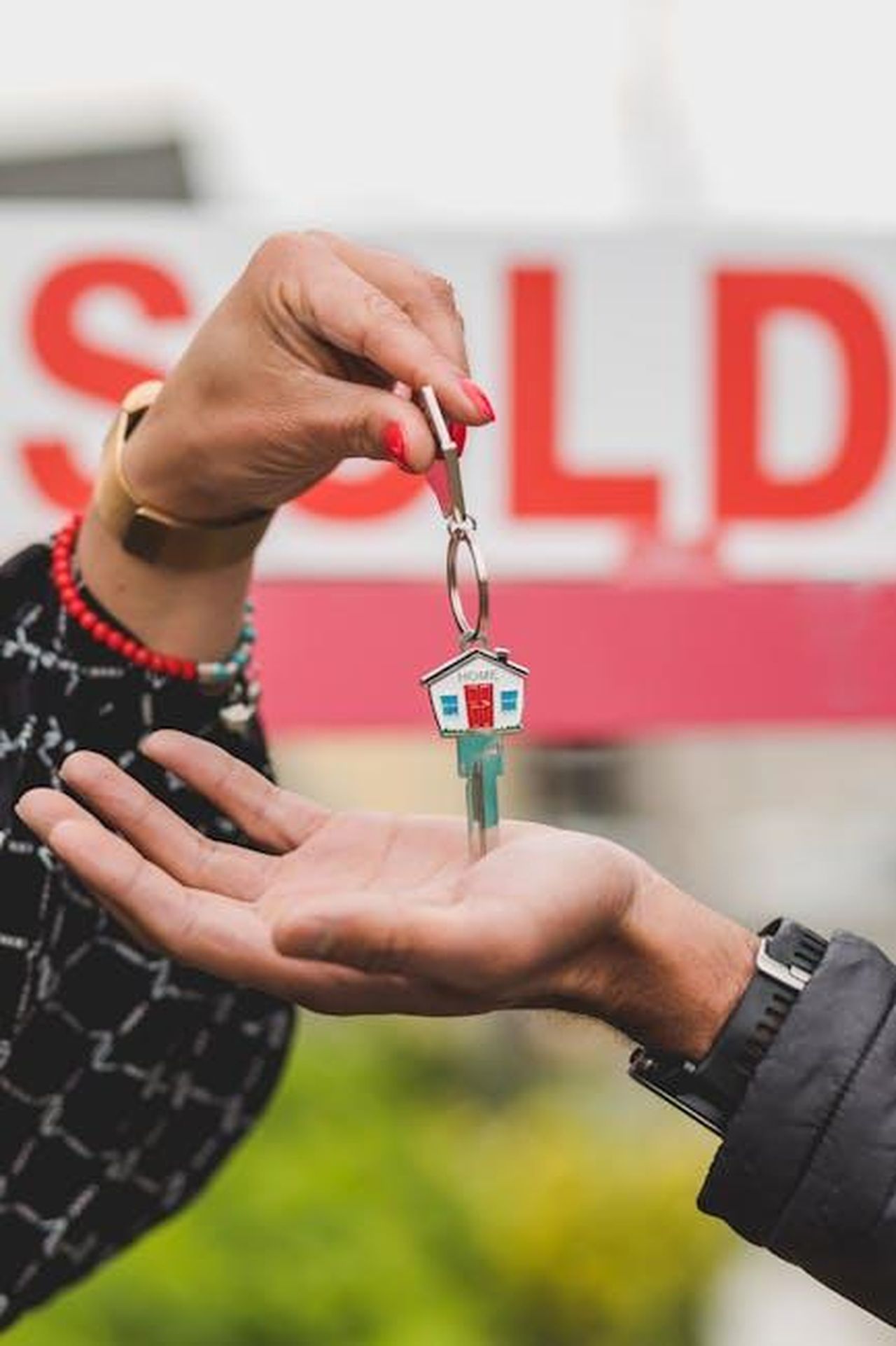 Lamentele_sui_cacciatori_di_case_difficili_rQw7TaOZmM - Confidenze24 Source: RDNE Stock project - pexels - Close-up of hands exchanging house key with colorful SOLD sign in the background.