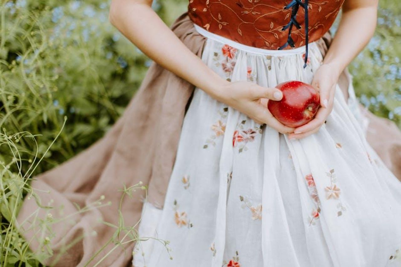 Lancio_della_collezione_Lilly_Hearts_Disney_sR1IgDko0r - Confidenze24 Source: Leah Newhouse - pexels - Elegant portrayal of a woman holding an apple, inspired by fairy tales.