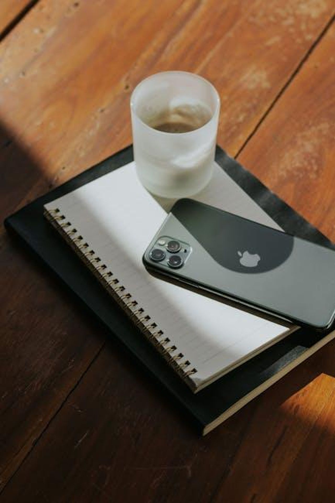 Lascia_una_lettera_UV5ITzeO3u - Confidenze24 Source: Letícia Alvares - pexels - A neatly arranged office desk features a smartphone, notebook, and glass of water, capturing a minimalist aesthetic.