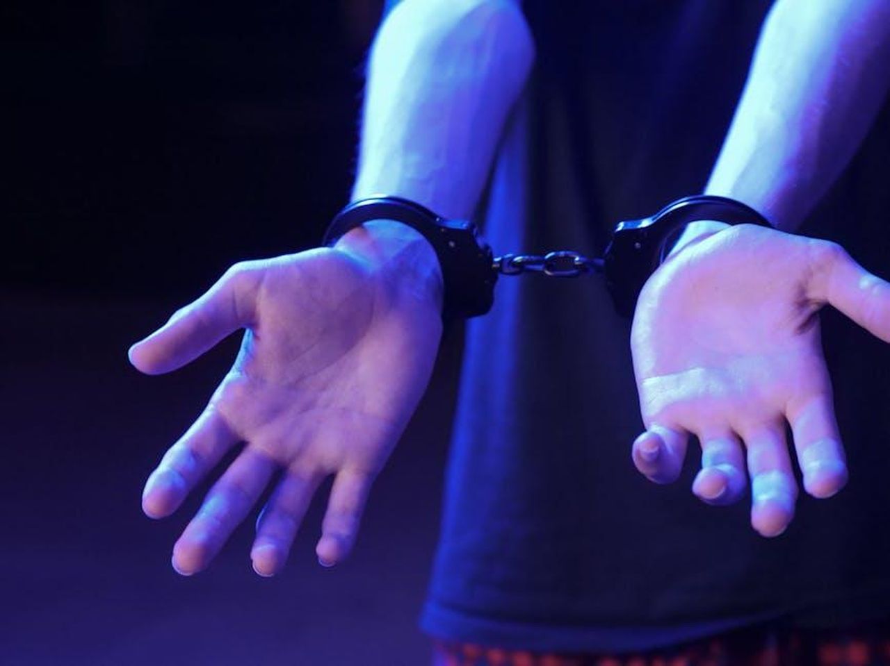 Lazione_legale_di_Jeff_2KYQBEOhBU - Confidenze24 Source: Kindel Media - pexels - Close-up of handcuffed hands in dramatic lighting symbolizes law enforcement and justice.