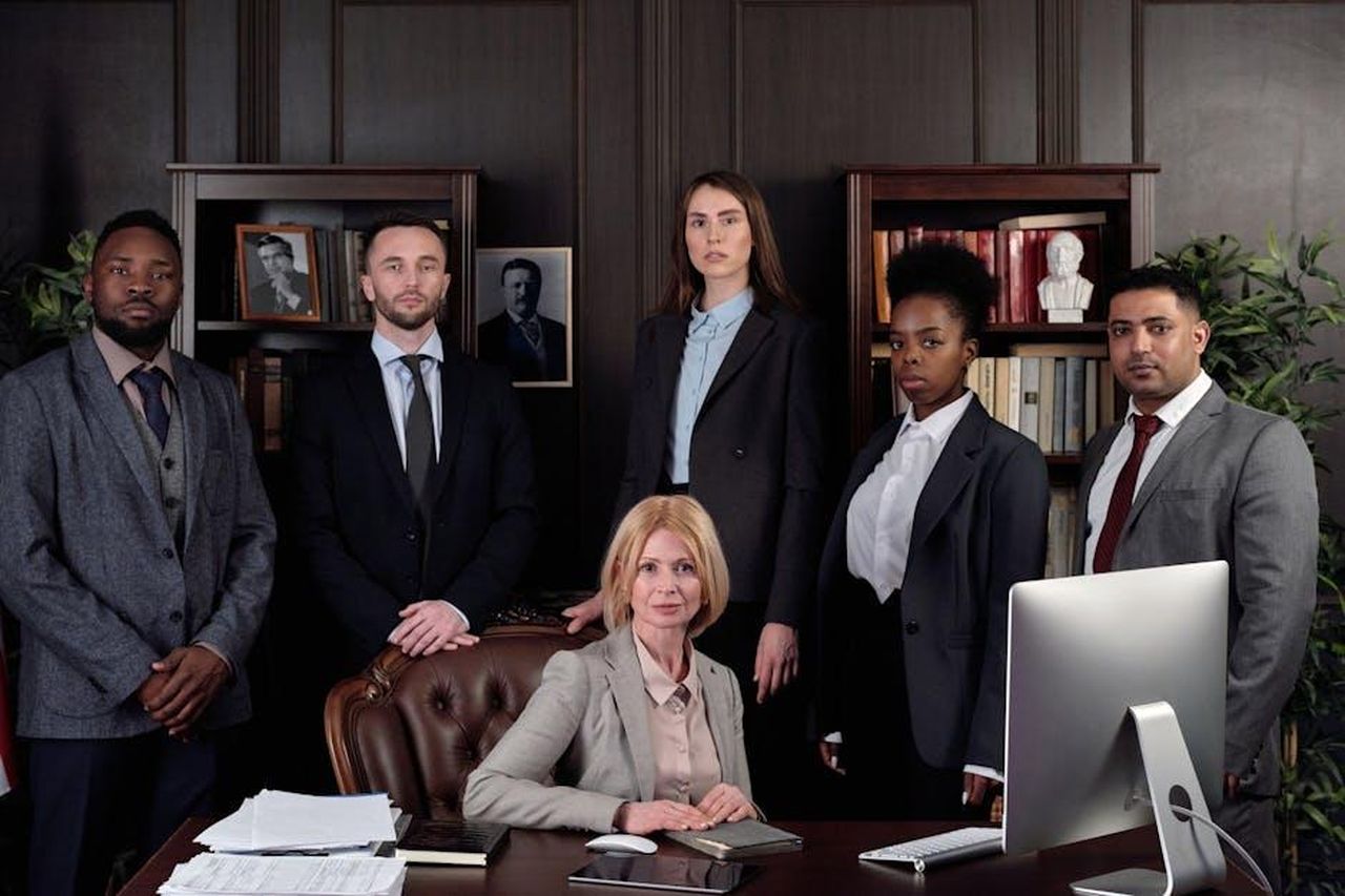 Le_Dichiarazioni_degli_Avvocati_di_UMG_uYa1ScPVGb - Confidenze24 Source: August de Richelieu - pexels - Diverse group of professionals in corporate attire posing confidently in an office environment.