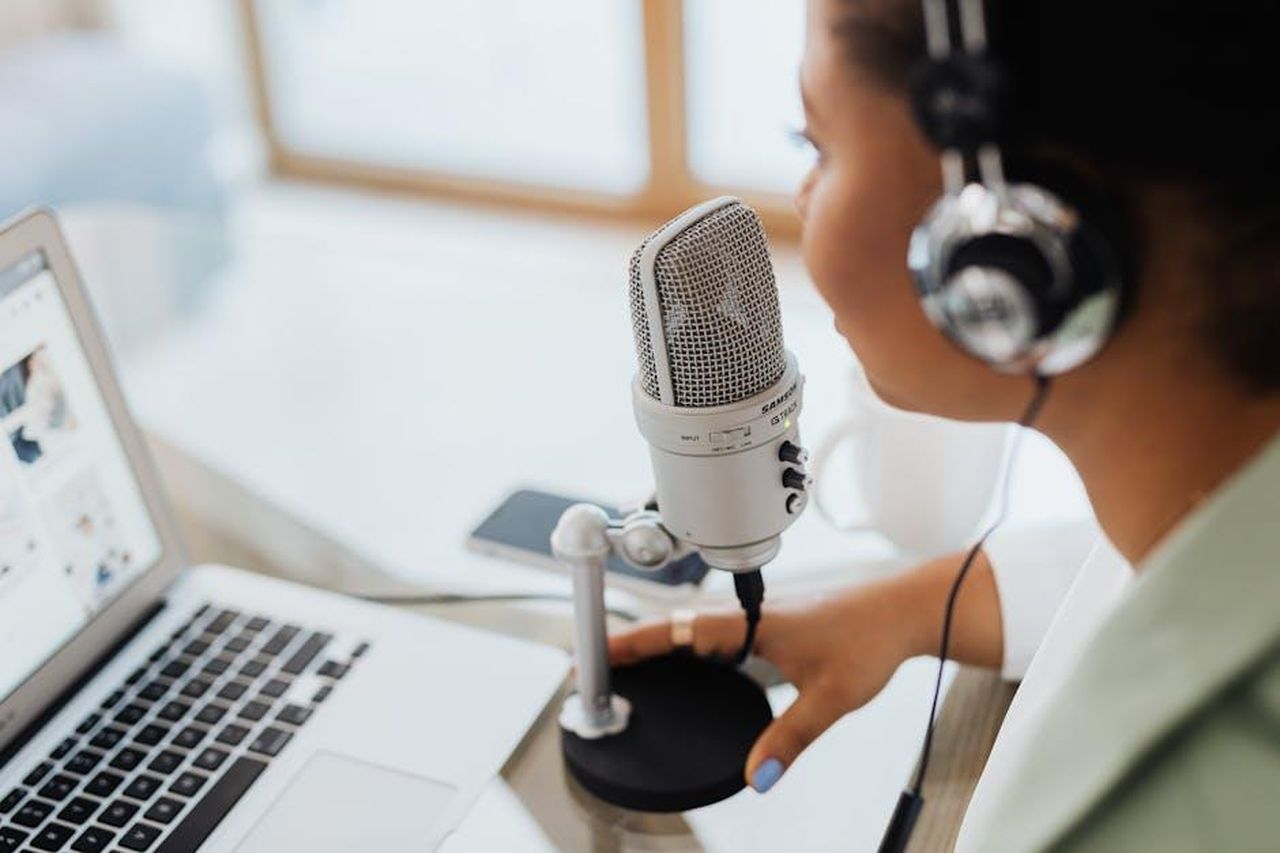 Le_Riflessioni_di_Kelly_Ripa_Z8oVZlYnIn - Confidenze24 Source: Photo By: Kaboompics.com - pexels - Professional woman recording a podcast or broadcast using a microphone and laptop at a desk.