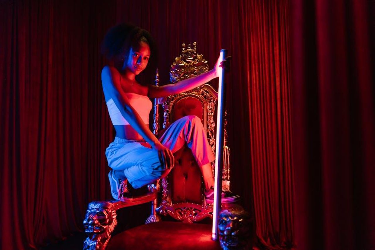Le_accuse_contro_Ben_Mezzenga_su_TikTok_9L2d0brnrX - Confidenze24 Source: RDNE Stock project - pexels - Striking portrait of a woman poised on a gold throne, illuminated by vibrant stage lighting.