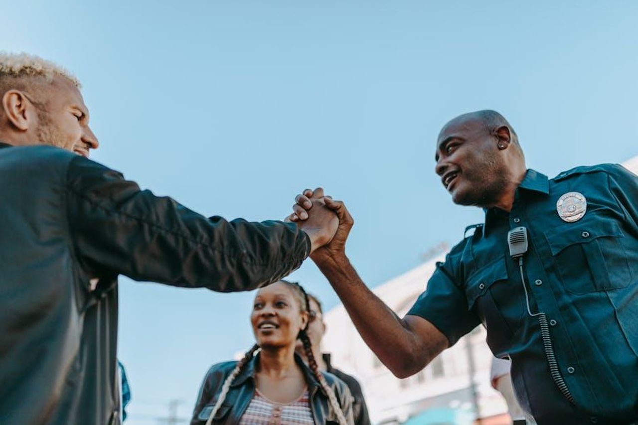 Le_accuse_contro_Victoria_Goodwin_e6e851WhNM - Confidenze24 Source: RDNE Stock project - pexels - A friendly handshake between a police officer and a civilian during an outdoor community event.