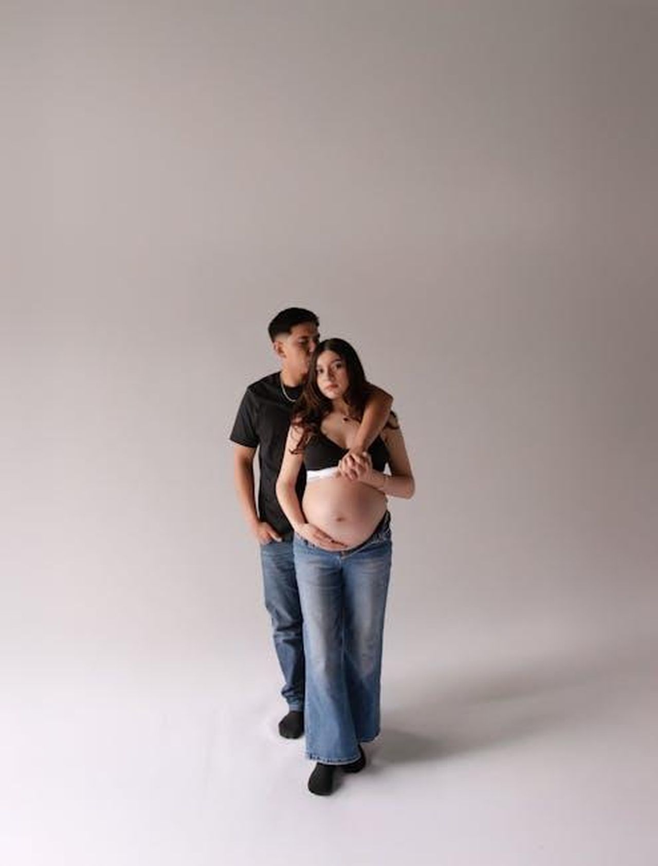 Le_complicazioni_della_gravidanza_di_Cori_mMvQevbUuY - Confidenze24 Source: Carlos Santiago - pexels - Expectant couple in casual attire lovingly embracing in a professional studio setting.