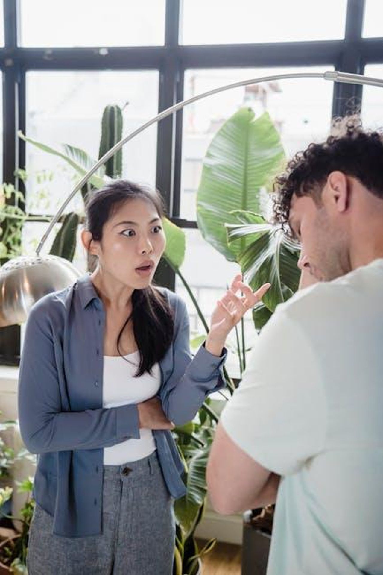 Le_complicazioni_della_relazione_tra_Ana_de_Armas_e_Ben_Affleck_MVfwWCB2Gu - Confidenze24 Source: Timur Weber - pexels - A couple engaged in a heated discussion in a room with lush indoor plants.
