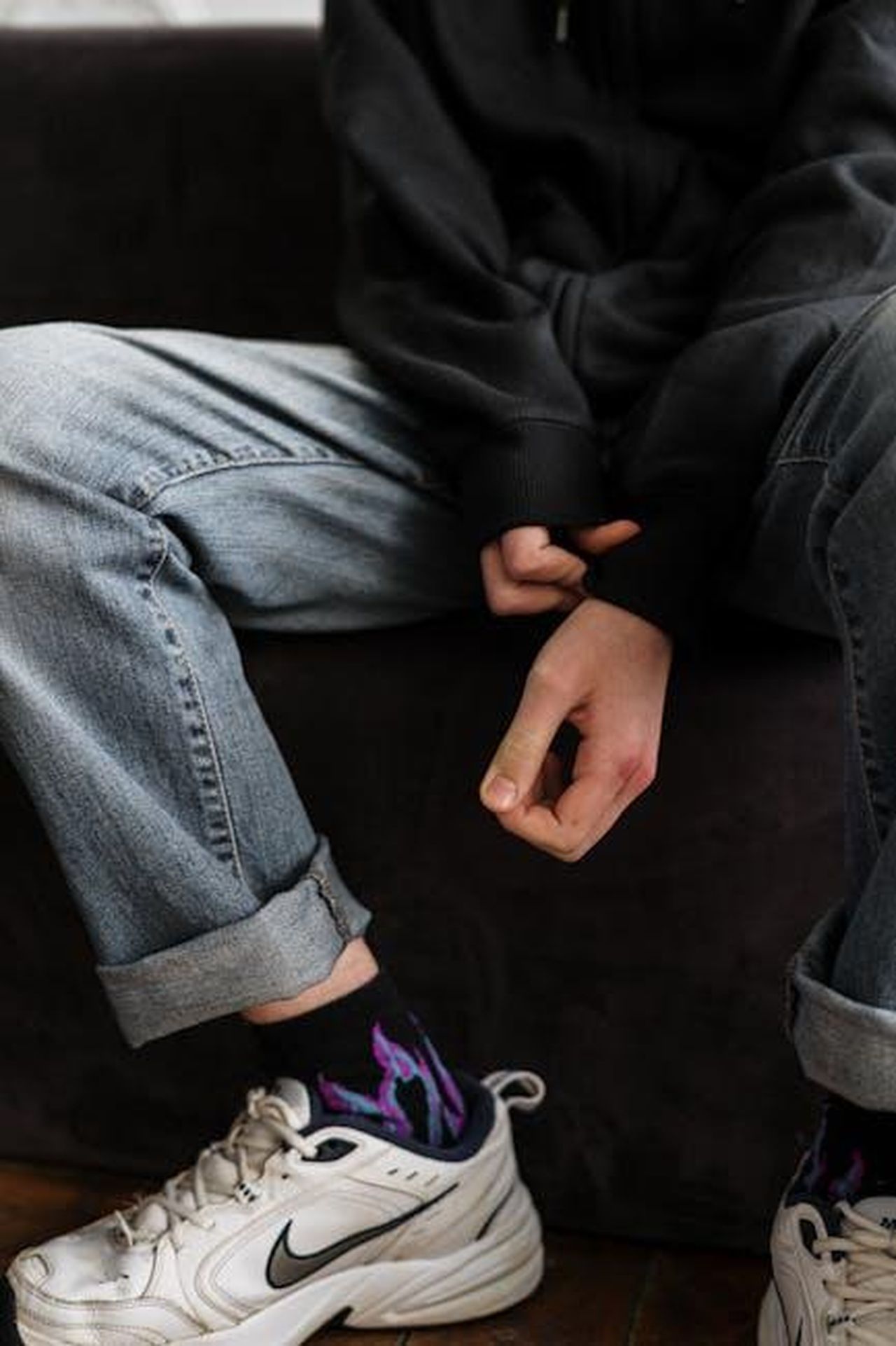 Le_conseguenze_del_trauma_di_Unique_QPaY3iZEAZ - Confidenze24 Source: cottonbro studio - pexels - Teenager in a hoodie and jeans sitting casually indoors with crossed arms and white sneakers.