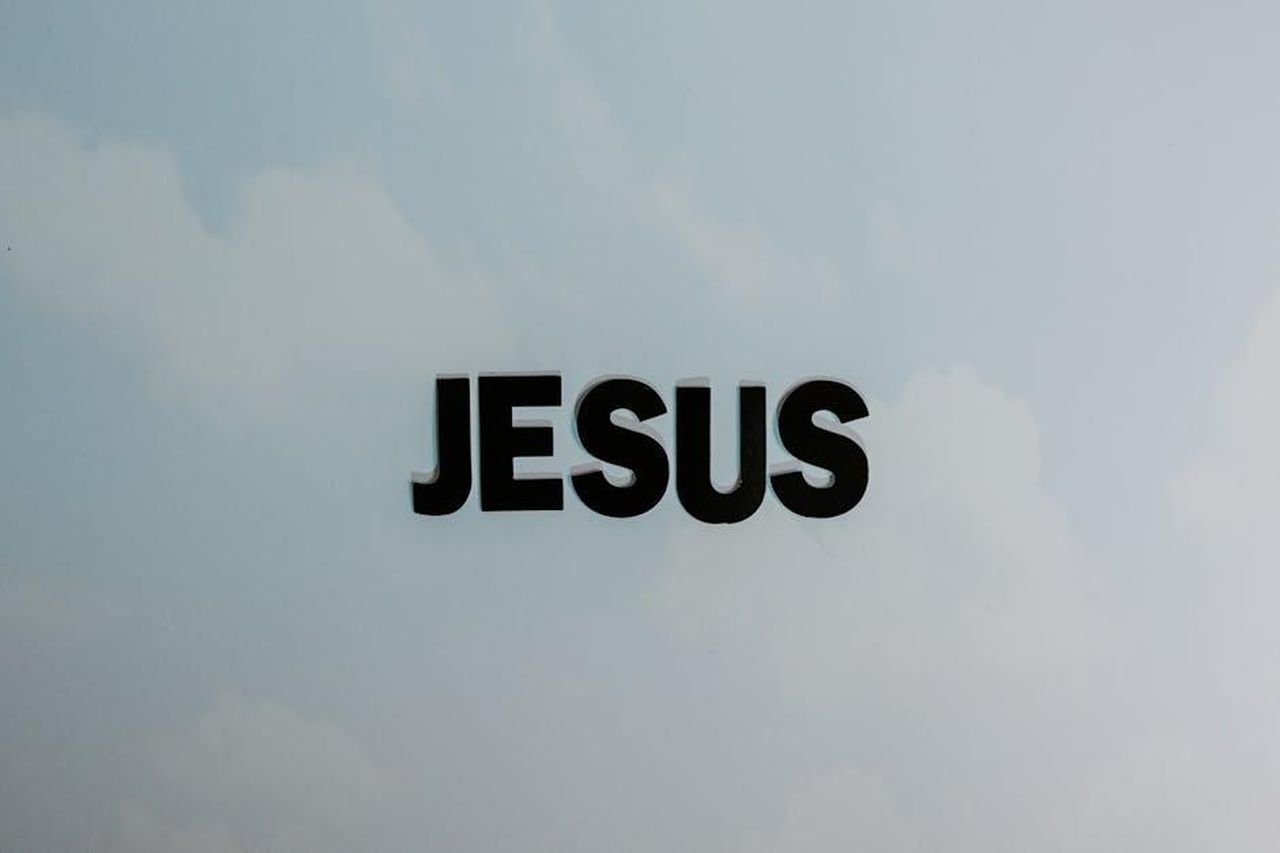 Le_convinzioni_religiose_di_Benson_Boone_KIbLzOMylL - Confidenze24 Source: Tara Winstead - pexels - Minimalist image with bold 'JESUS' text against a cloudy sky background.