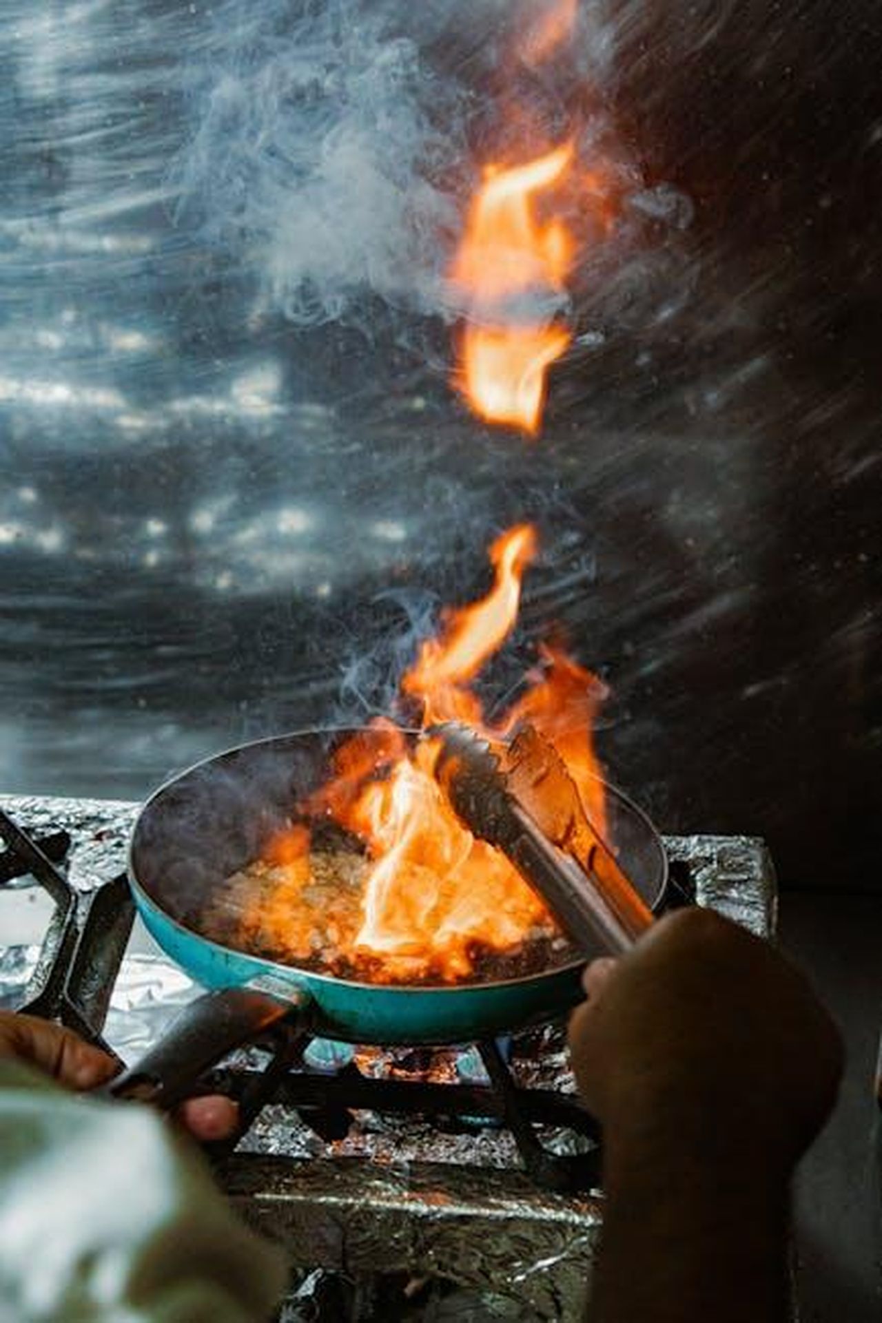 Le_critiche_di_Prue_Leith_al_nuovo_show_di_Meghan_D8LQUY0XwM - Confidenze24 Source: pedro furtado - pexels - Chef using tongs to flambé dish on stove, dramatic fire for culinary skills.