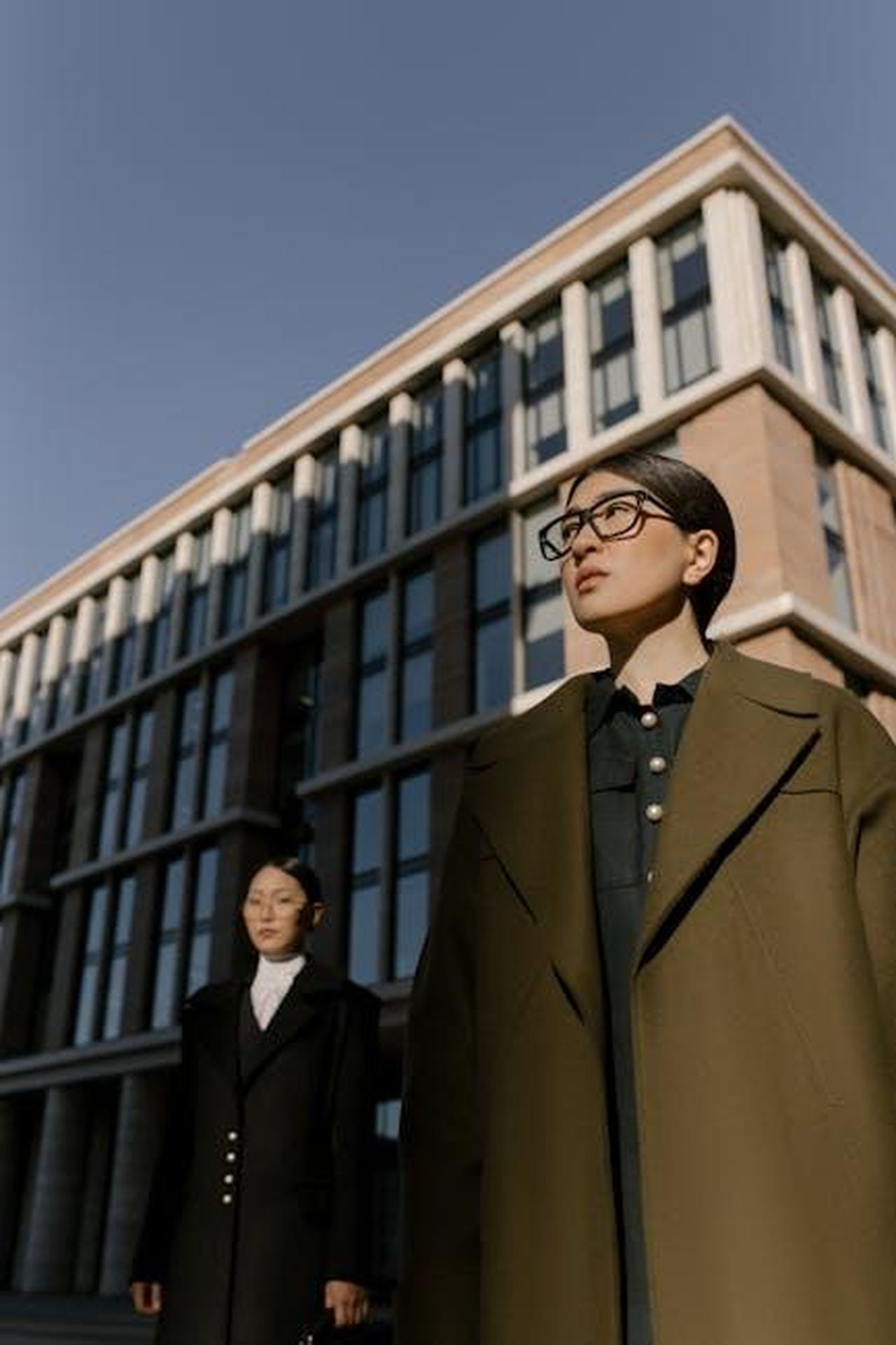 Le_dichiarazioni_dellavvocato_di_Jane_Doe_zFy47eak4c - Confidenze24 Source: cottonbro studio - pexels - Two businesswomen in elegant coats stand confidently outside a modern office building.