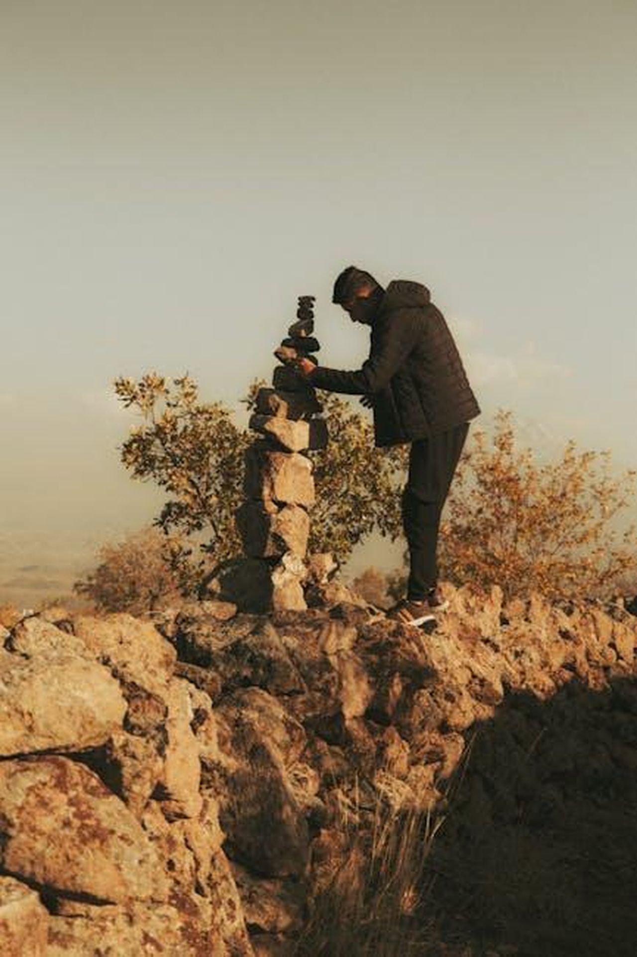Le_dichiarazioni_di_Ben_Shapiro_tcFYROMBEO - Confidenze24 Source: RIDVAN AYRIK - pexels - A man building a stone cairn in İncesu, Kayseri, Türkiye during sunset.