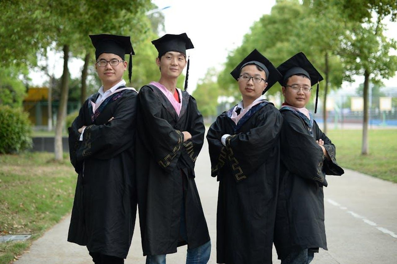 Le_dichiarazioni_di_Boosie_sulla_borsa_di_studio_kCPKqs9ucn - Confidenze24 Source: cero cero - pexels - Four male graduates in cap and gown pose outdoors, celebrating achievement.