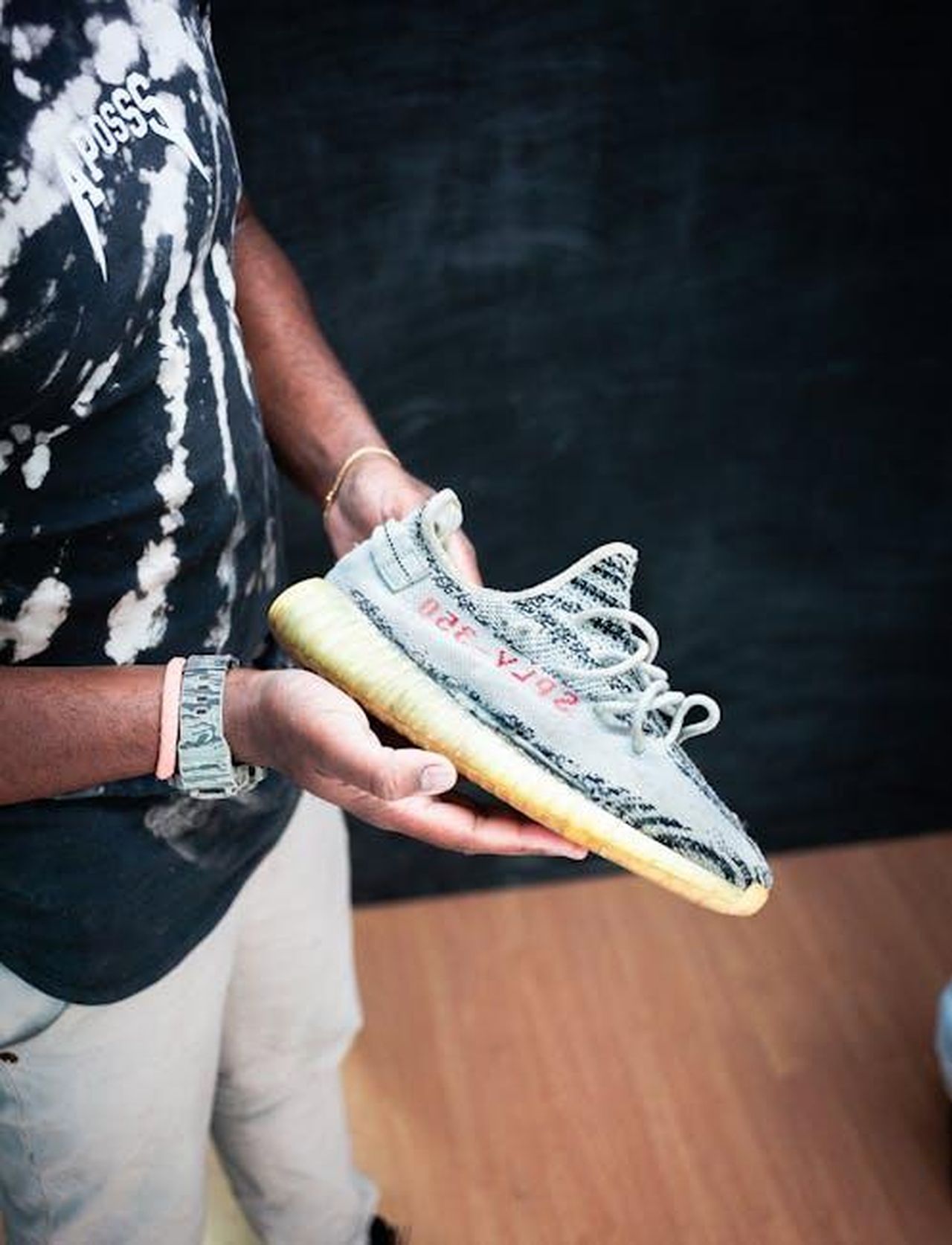 Le_dichiarazioni_di_Kanye_West_e_la_reazione_di_Tina_qpP64BKSYf - Confidenze24 Source: Deybson Mallony - pexels - Close-up of a person holding Yeezy Boost sneakers indoors, showcasing fashion style.