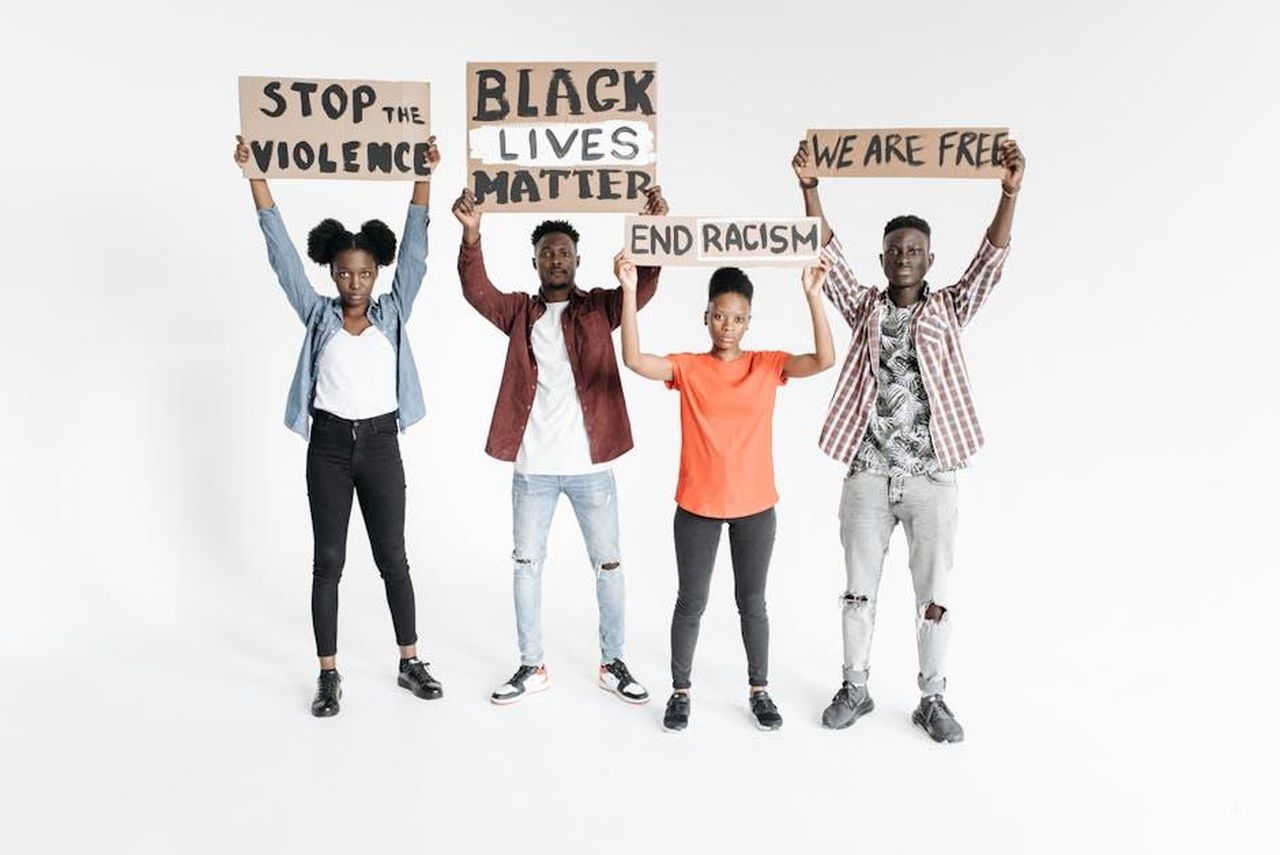 Le_dichiarazioni_di_Wendy_Williams_WNxJ1syq3h - Confidenze24 Source: Pavel Danilyuk - pexels - Four diverse individuals holding protest signs about social justice on a white background.