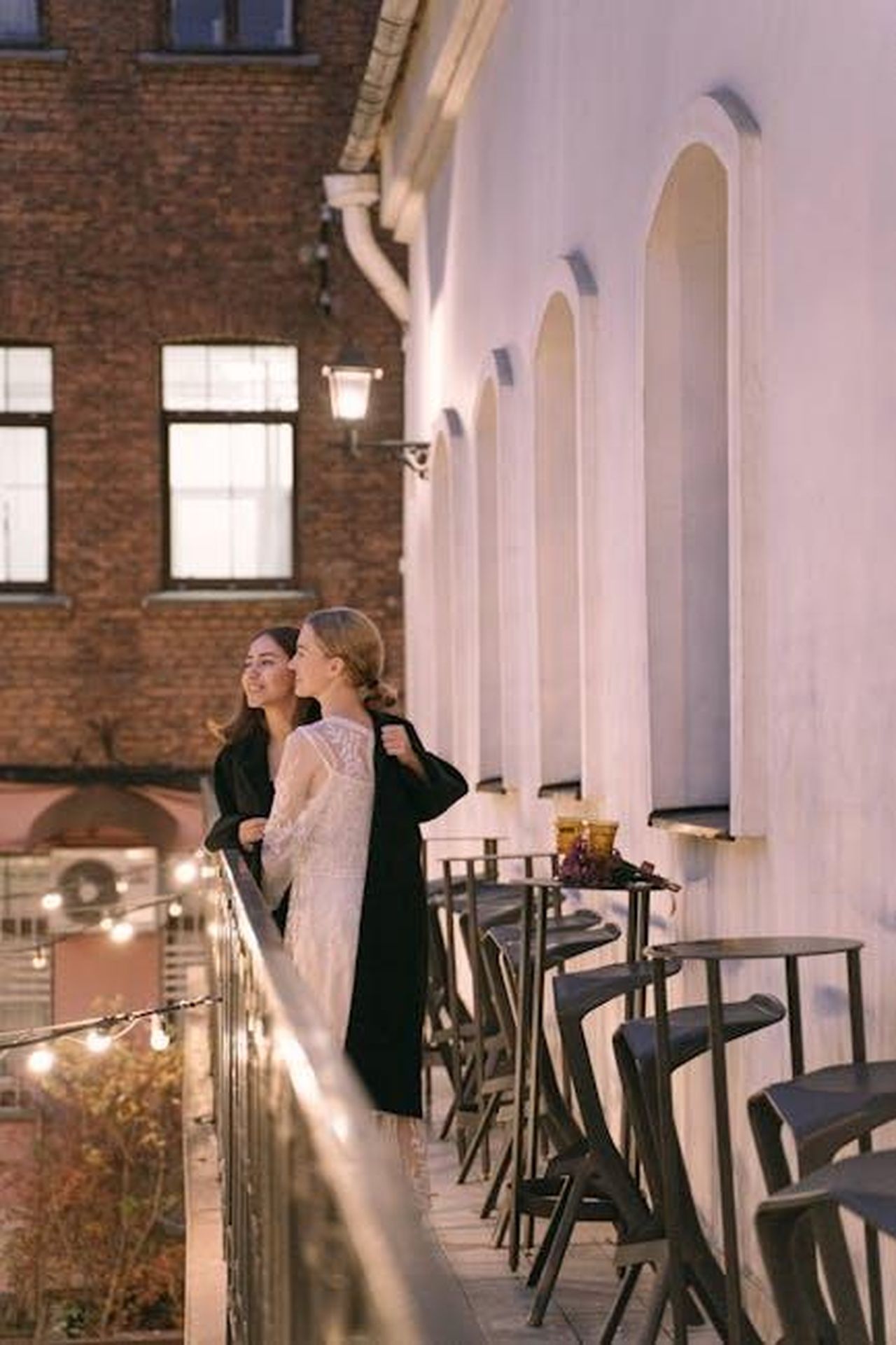Le_difficolt_di_essere_la_fidanzata_di_una_celebrit_ILXgJfQCOr - Confidenze24 Source: Ivan Samkov - pexels - Two women enjoying a romantic evening on a city balcony, gazing at the view.