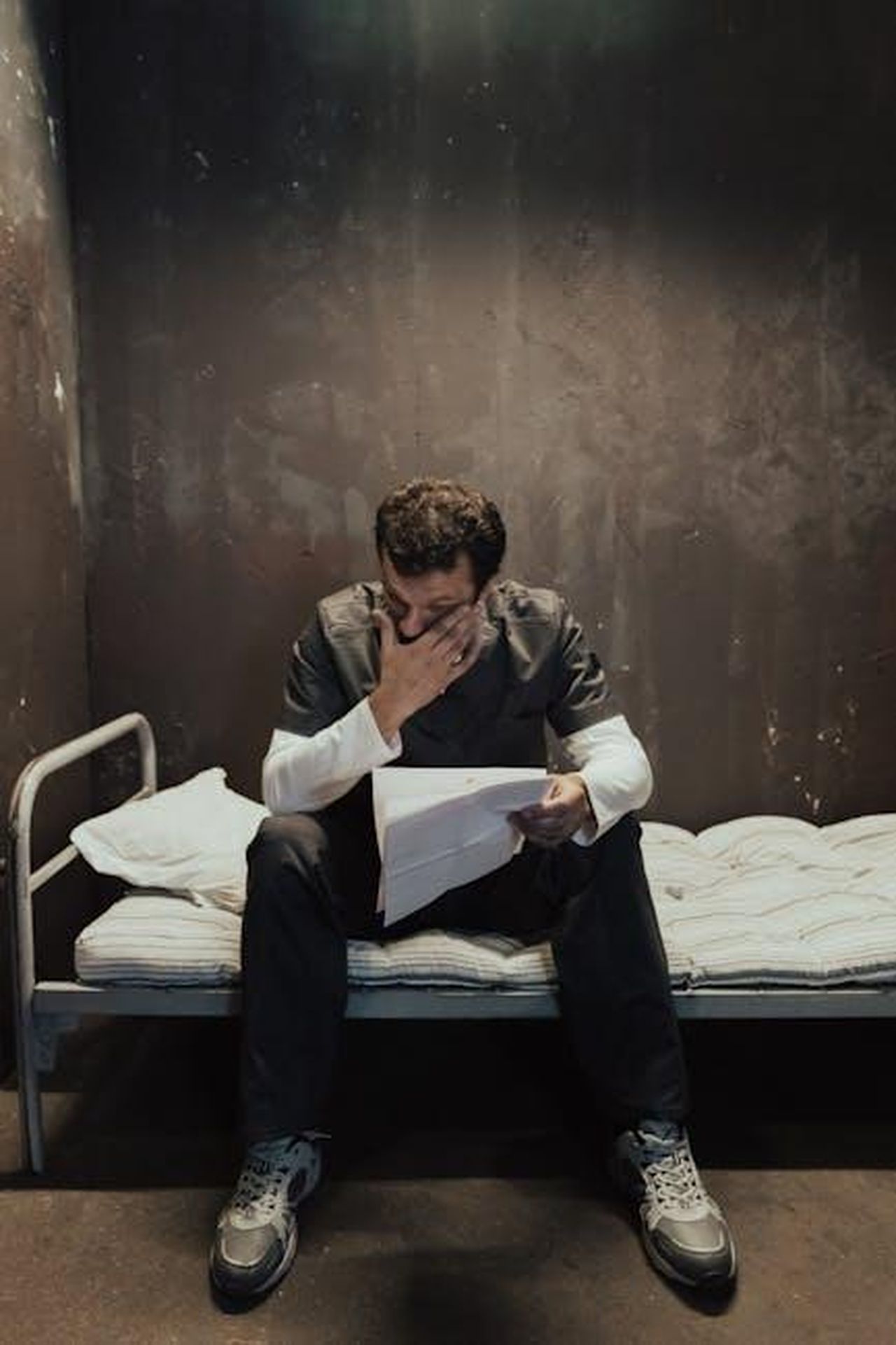 Le_difficolt_legali_di_Jonathan_Majors_rpheOYzWDu - Confidenze24 Source: Ron Lach - pexels - An emotional prisoner sitting on a bed in his cell, reading a letter.