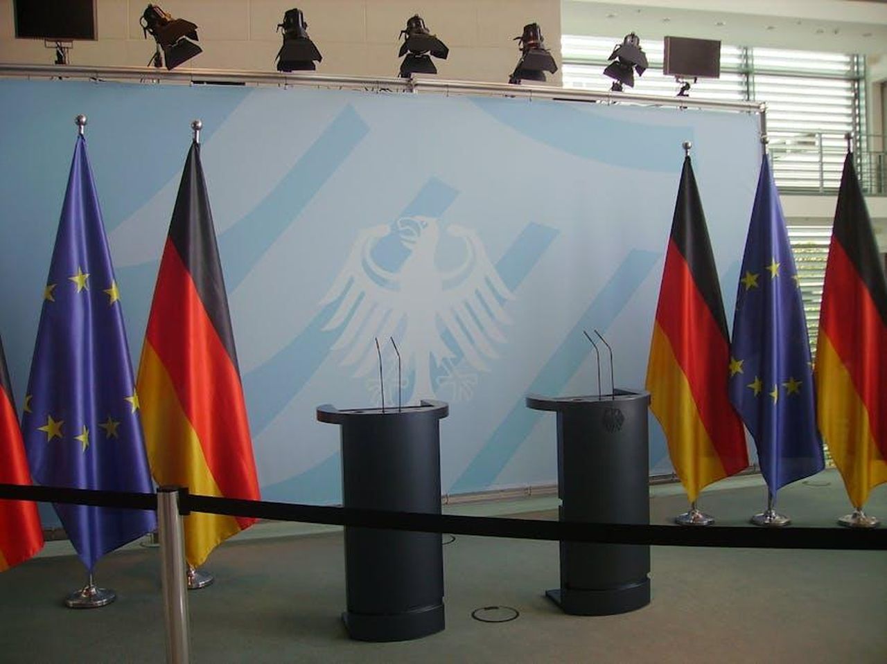 Le_divergenze_politiche_tra_Sara_e_Ben_26JABeCOtz - Confidenze24 Source: Wikimedia Commons - pexels - Empty podiums with German and EU flags in Federal Chancellery, Berlin.