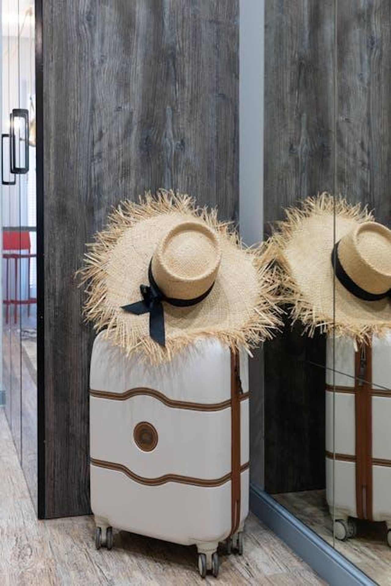 Le_foto_di_Sydney_Sweeney_e_il_suo_messaggio_di_autostima_CzZmx3hz0o - Confidenze24 Source: Max Vakhtbovycn - pexels - A chic straw hat resting on a suitcase in a contemporary hotel hallway, ready for travel.