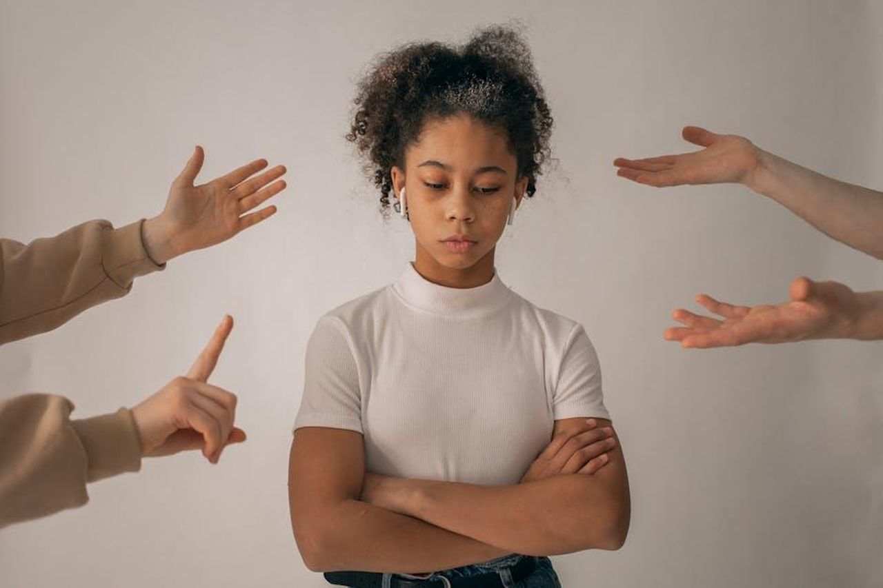 Le_implicazioni_familiari_e_sociali_della_scelta_del_padrino_l1HoW0T9Vs - Confidenze24 Source: Monstera Production - pexels - A teenage girl looks upset while expressive hands point and gesture around her.