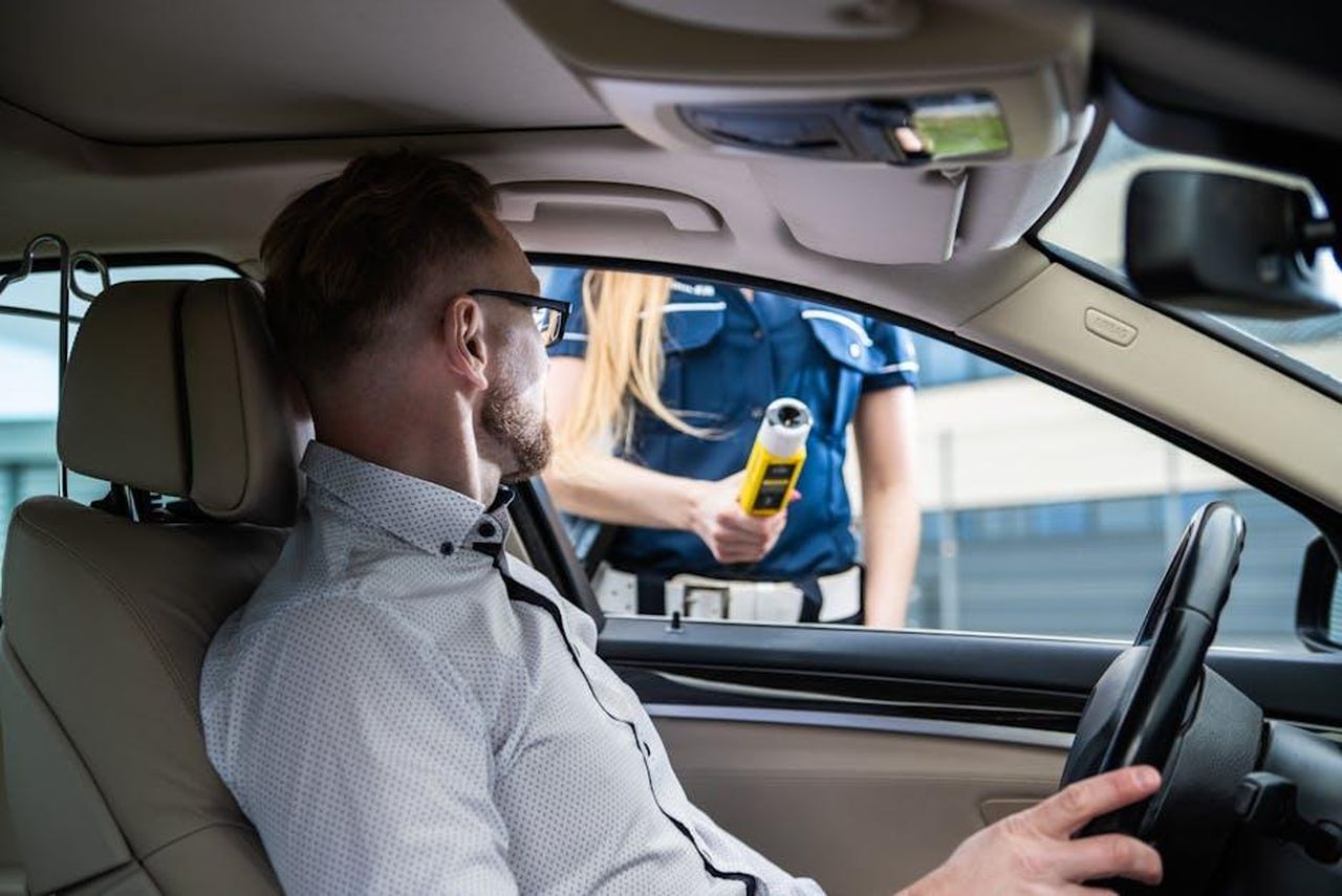 Le_implicazioni_legali_del_rilascio_UOK01dcdfV - Confidenze24 Source: Łukasz Promiler - pexels - Officer administering a breathalyzer test to a driver during a roadside check for safety.