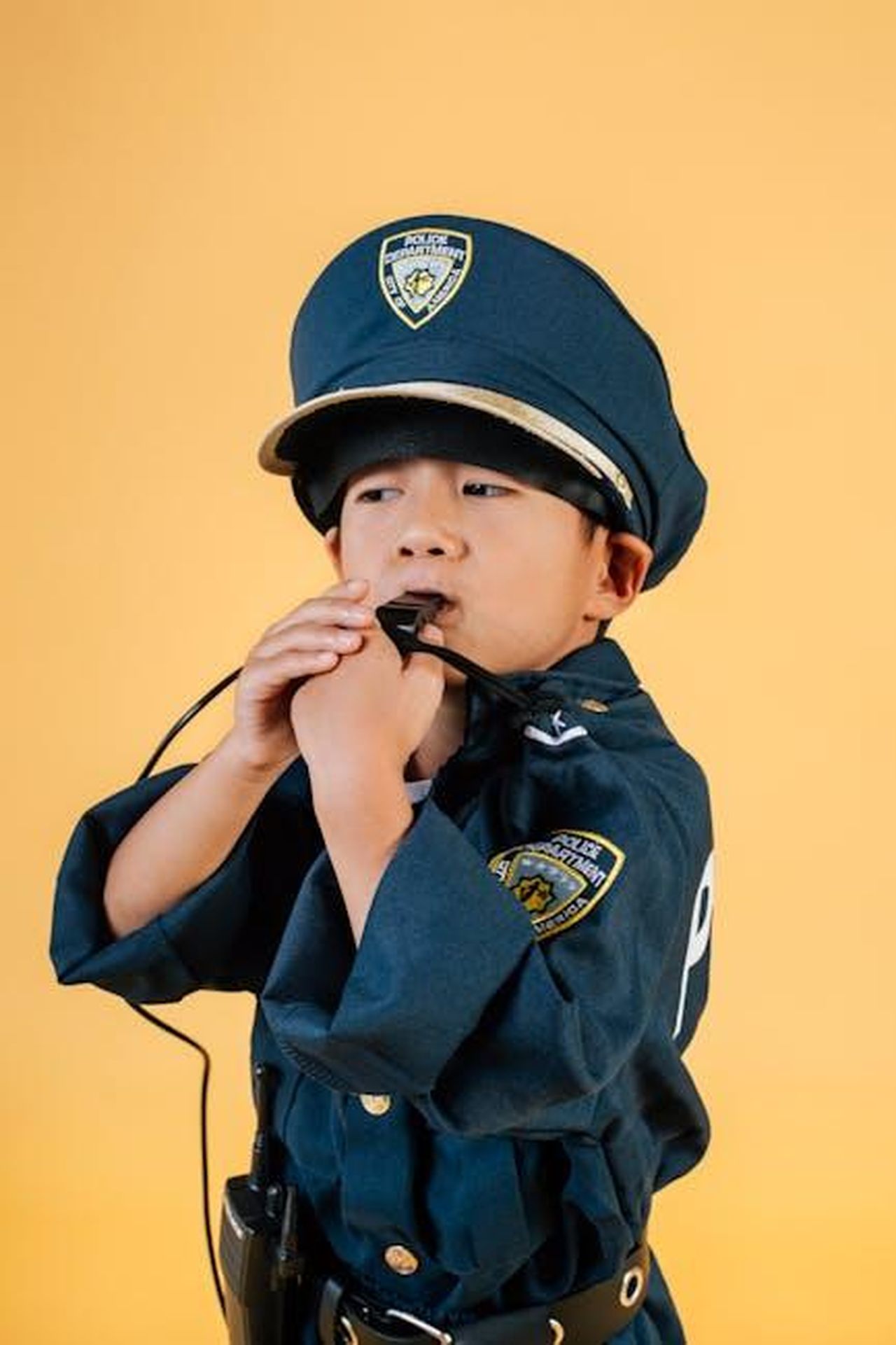 Le_nuove_leggi_in_Utah_per_proteggere_i_bambini_influencer_y9auh97135 - Confidenze24 Source: Amina Filkins - pexels - Focused ethnic kid in police uniform costume blowing whistle while standing in photo studio on yellow background and looking away