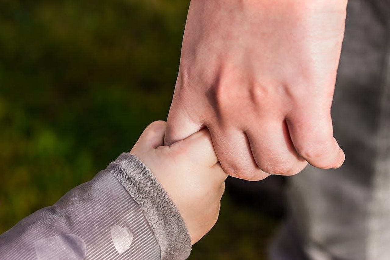 Le_opinioni_di_Jennifer_sui_suoi_figli_s0NeGlwaTM - Confidenze24 Source: Pixabay - pexels - A close-up of a child and parent holding hands in a park, symbolizing love and trust.