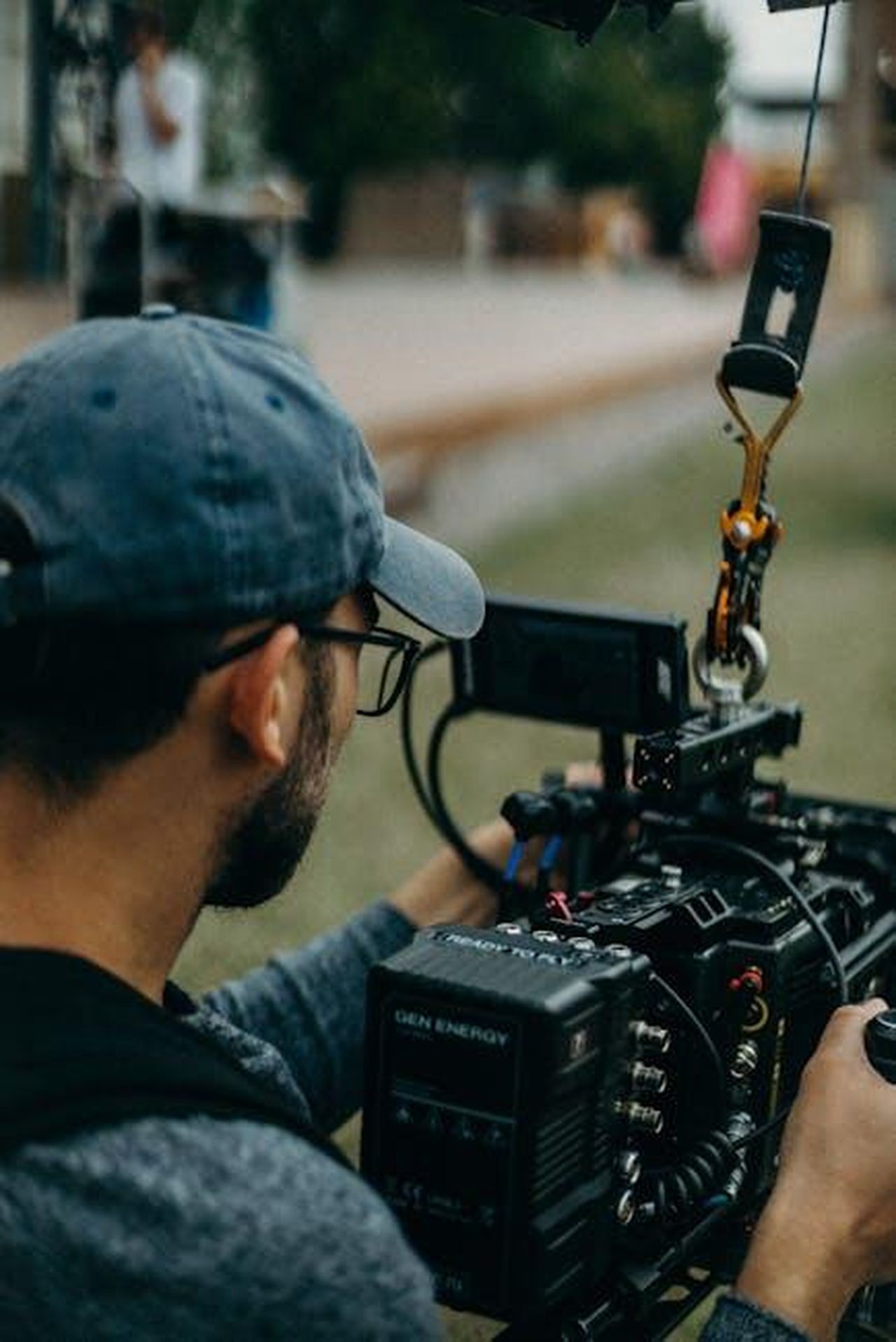 Le_parole_del_regista_Gavin_OConnor_AnH6yry9XP - Confidenze24 Source: cottonbro studio - pexels - A focused filmmaker operating a cinema camera outdoors during daylight, capturing a creative video shoot.