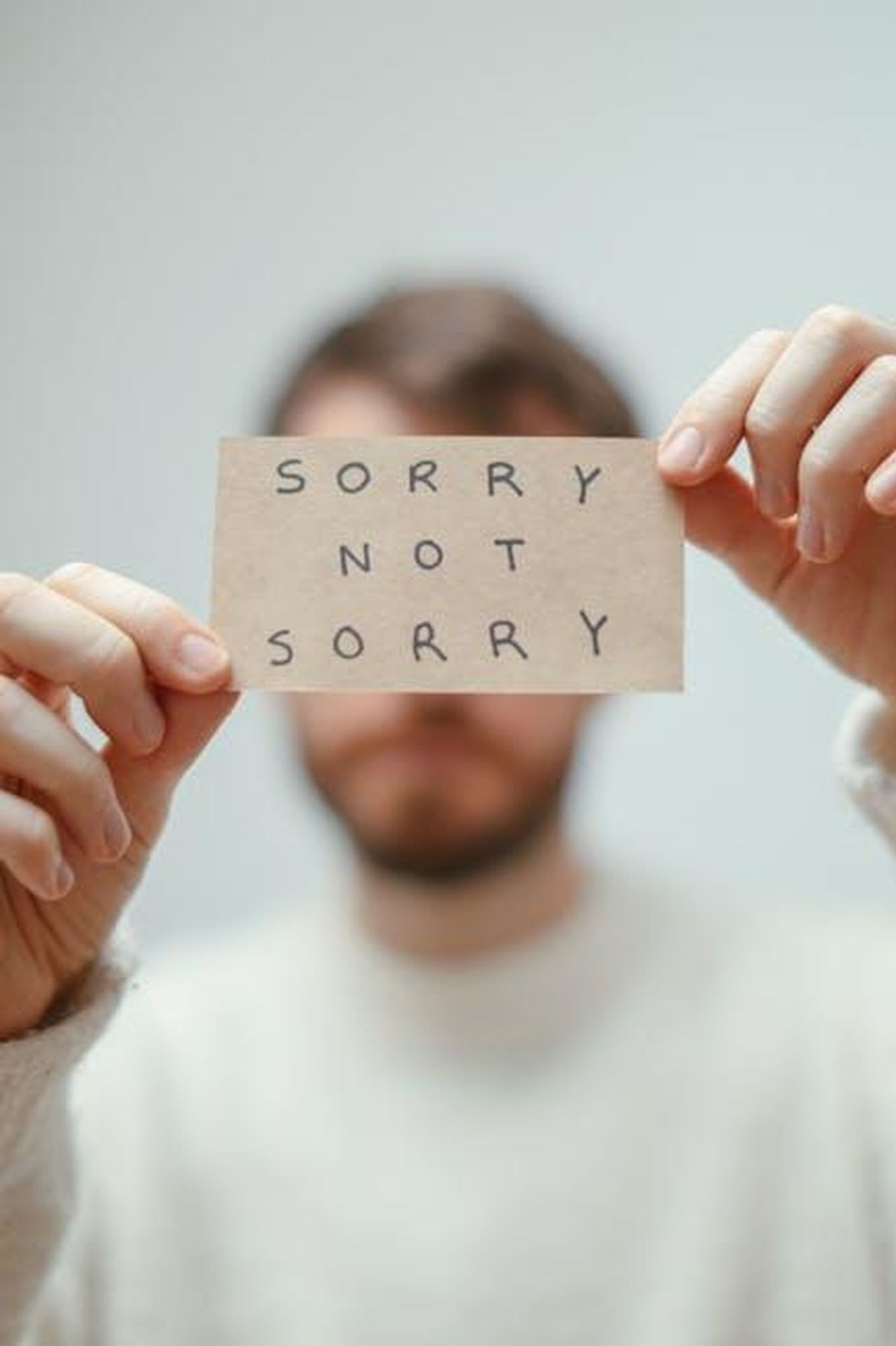 Le_reazioni_al_discorso_di_Adrien_Brody_26Whe6H29X - Confidenze24 Source: Cup of Couple - pexels - Blurred image of a man holding a card with the phrase 'Sorry Not Sorry'.