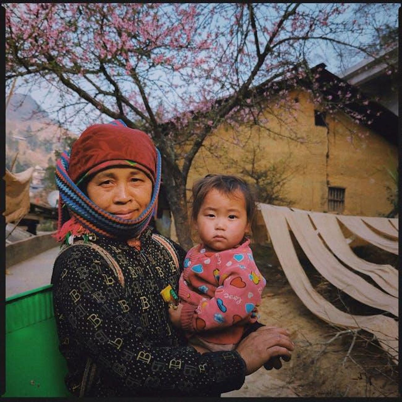Le_reazioni_dei_fan_e_lamore_per_la_famiglia_299pncpJwE - Confidenze24 Source: Duc Nguyen - pexels - A mother and child stand in a rural village with blossoming trees, evoking a warm, cultural scene.