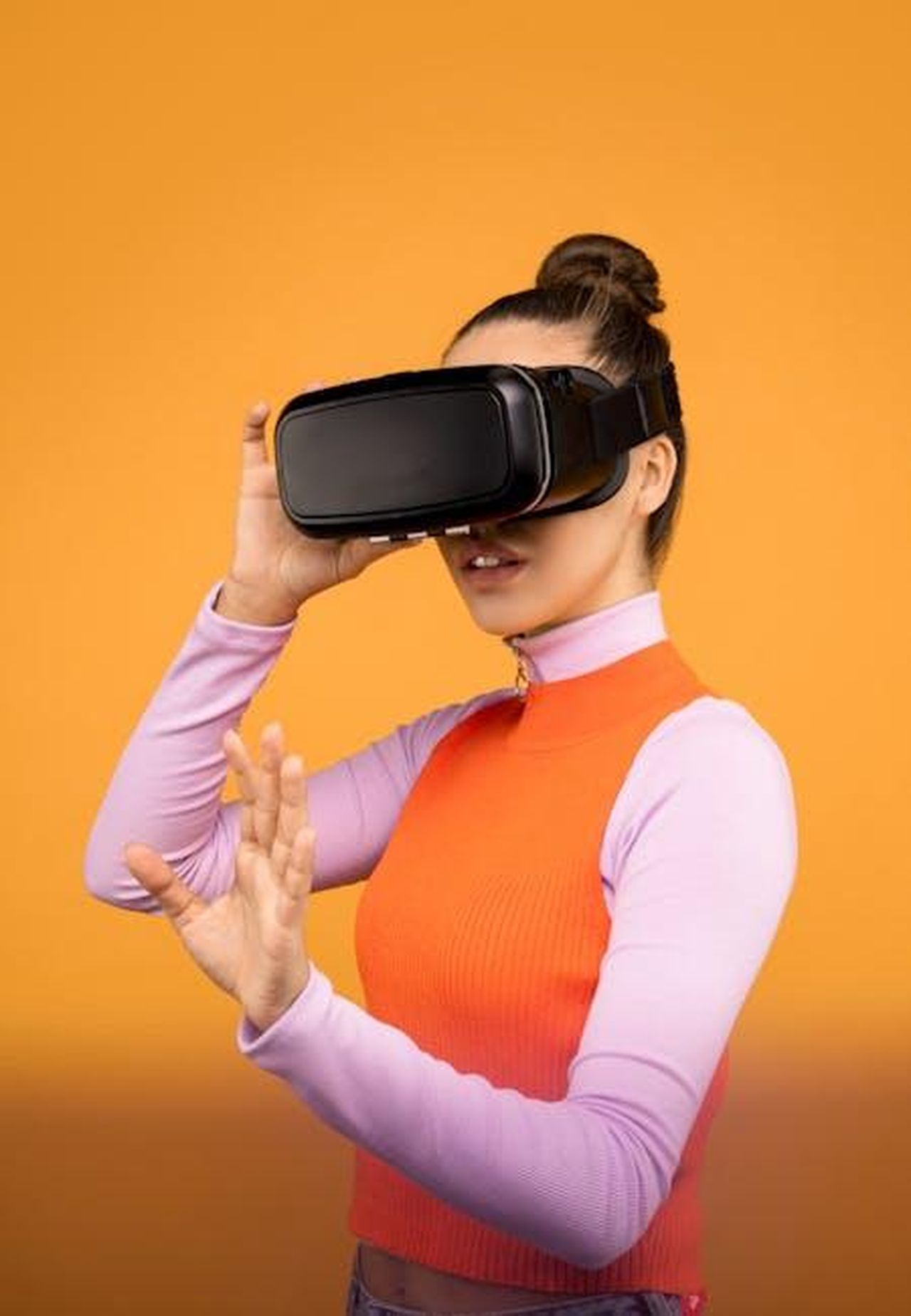 Le_reazioni_dei_tabloid_britannici_nXev6pY5N8 - Confidenze24 Source: Sound On - pexels - Woman immersed in virtual reality using VR headset against a vibrant orange background.