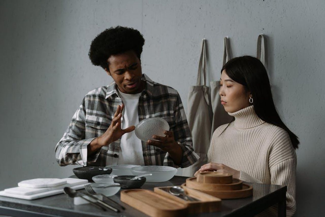 Le_recensioni_entusiaste_dei_consumatori_VE96wmIcPW - Confidenze24 Source: cottonbro studio - pexels - An African American man and Asian woman discussing modern tableware options in a stylish setting.